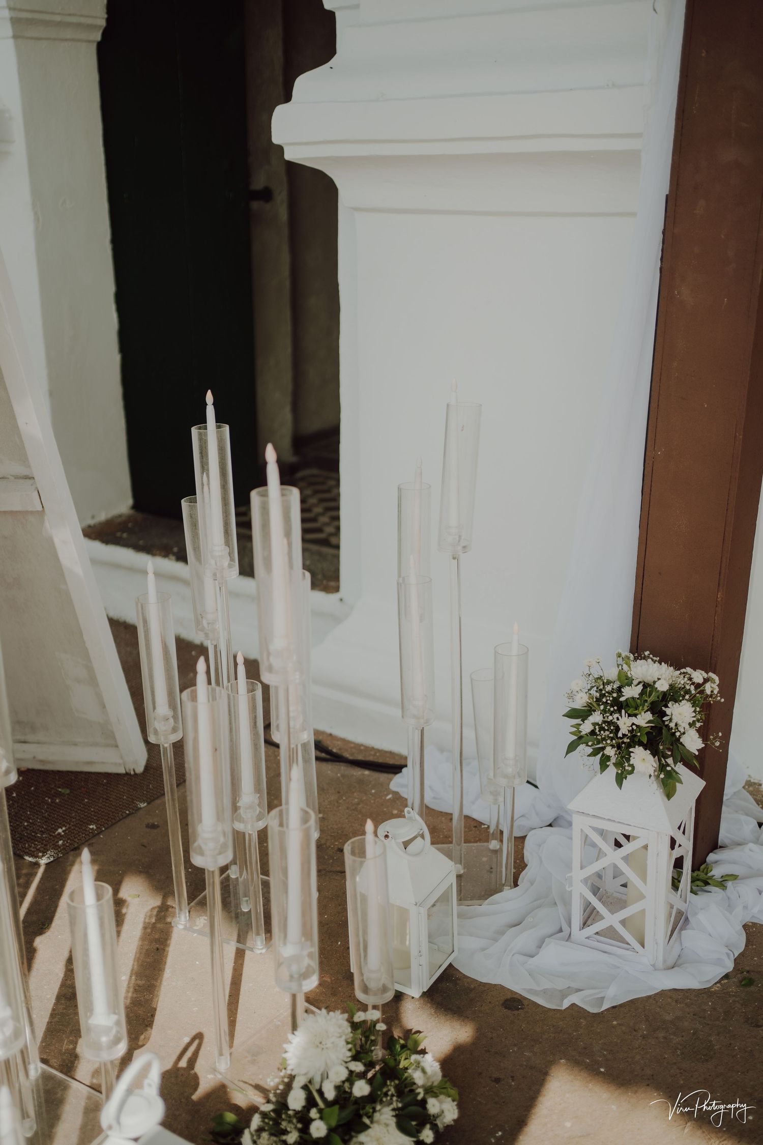 Elegant white lanterns and tall candles create a romantic wedding aisle decoration with delicate floral accents.