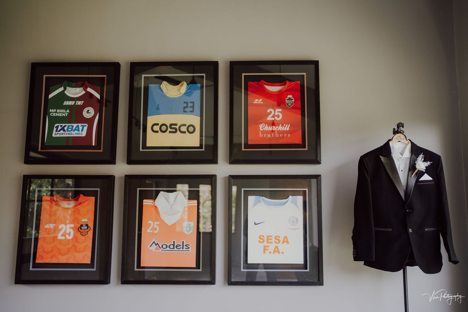 Framed sports jerseys displayed on a wall next to a black suit jacket with a white boutonniere.