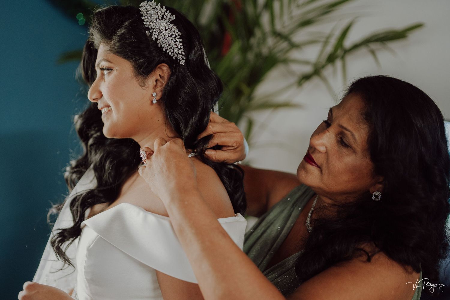 A bride in a white gown getting help with her dress while getting ready on her wedding day.