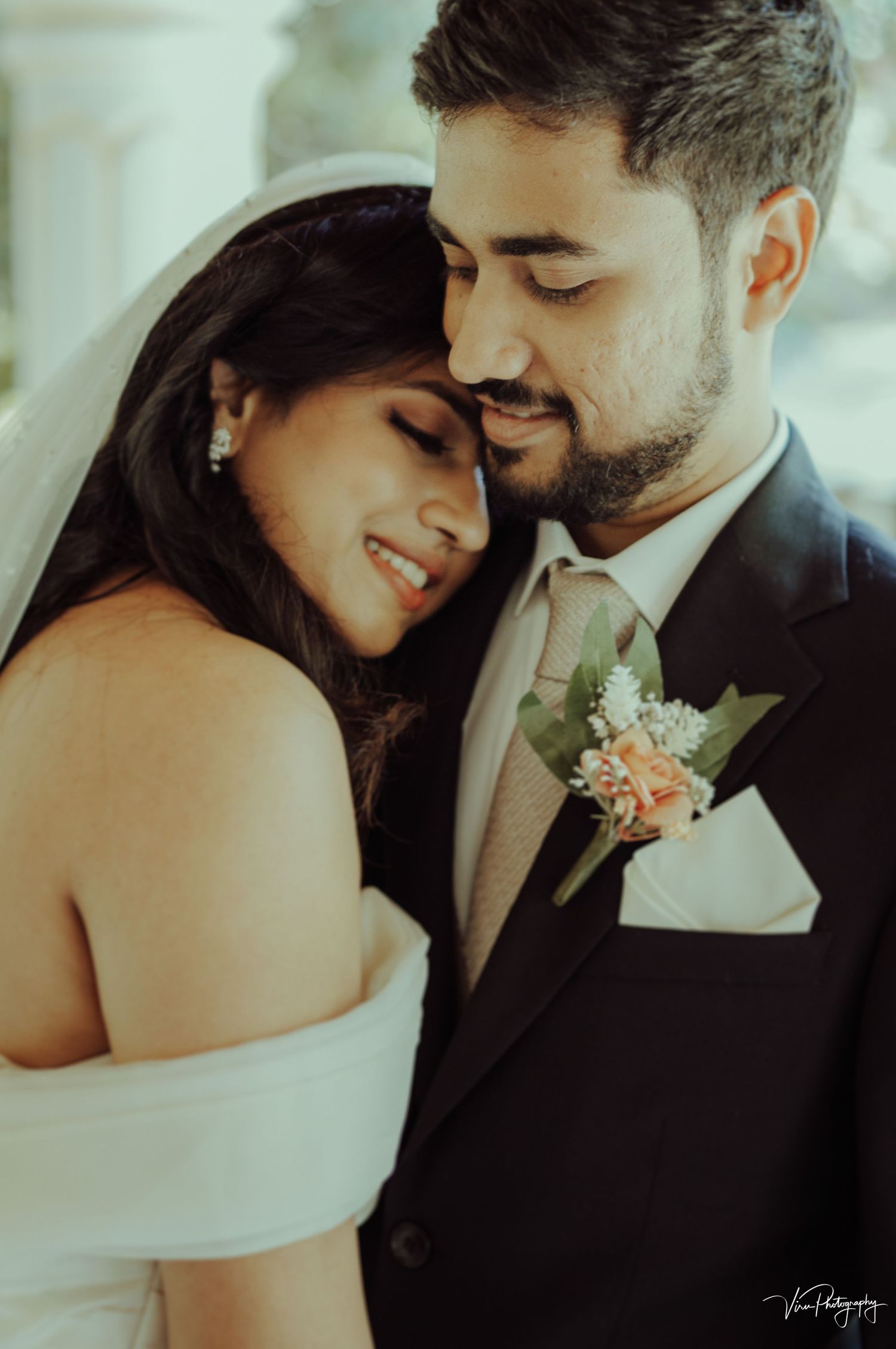 A romantic wedding couple sharing an intimate moment with the groom wearing a boutonniere and bride in an off-shoulder dress.