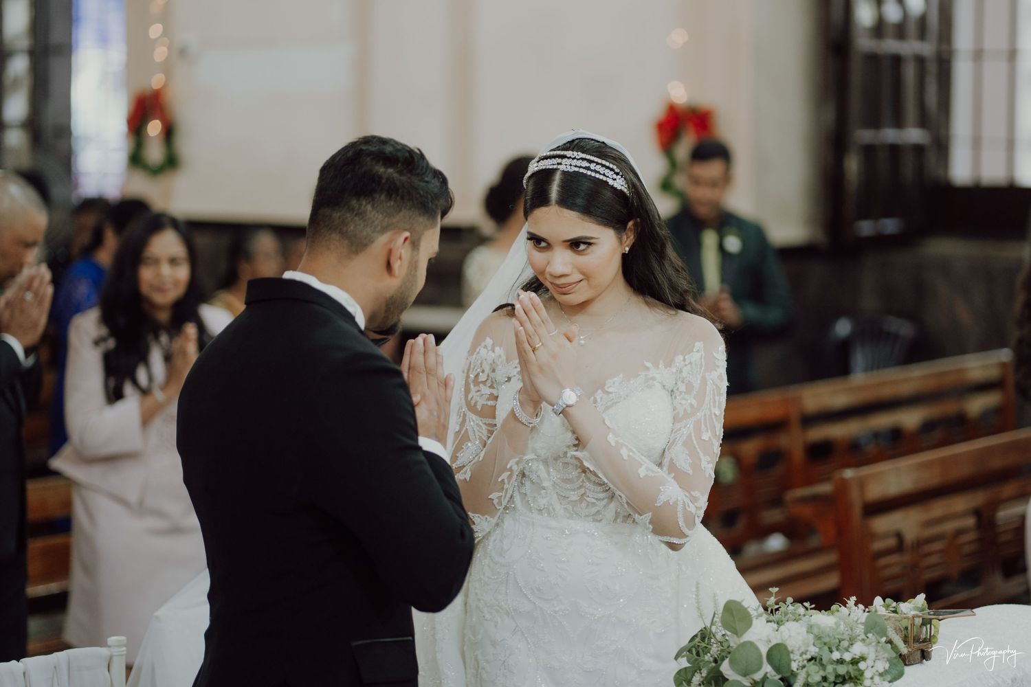 A couple shares an emotional moment during their wedding ceremony inside a church decorated with poinsettias.
