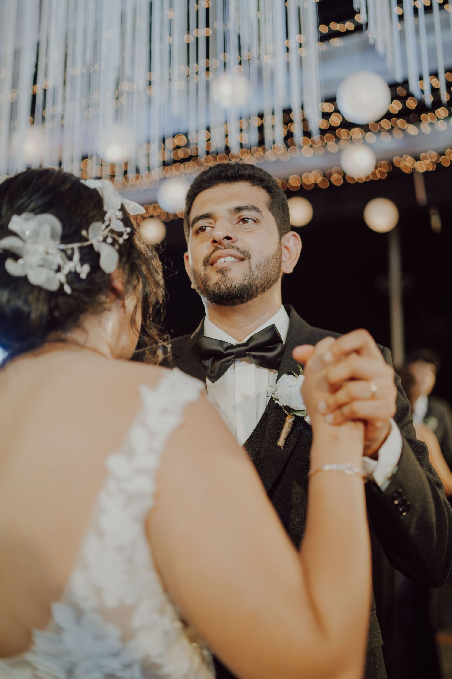 Intimate first dance moment under hanging lights and white fabric draping.