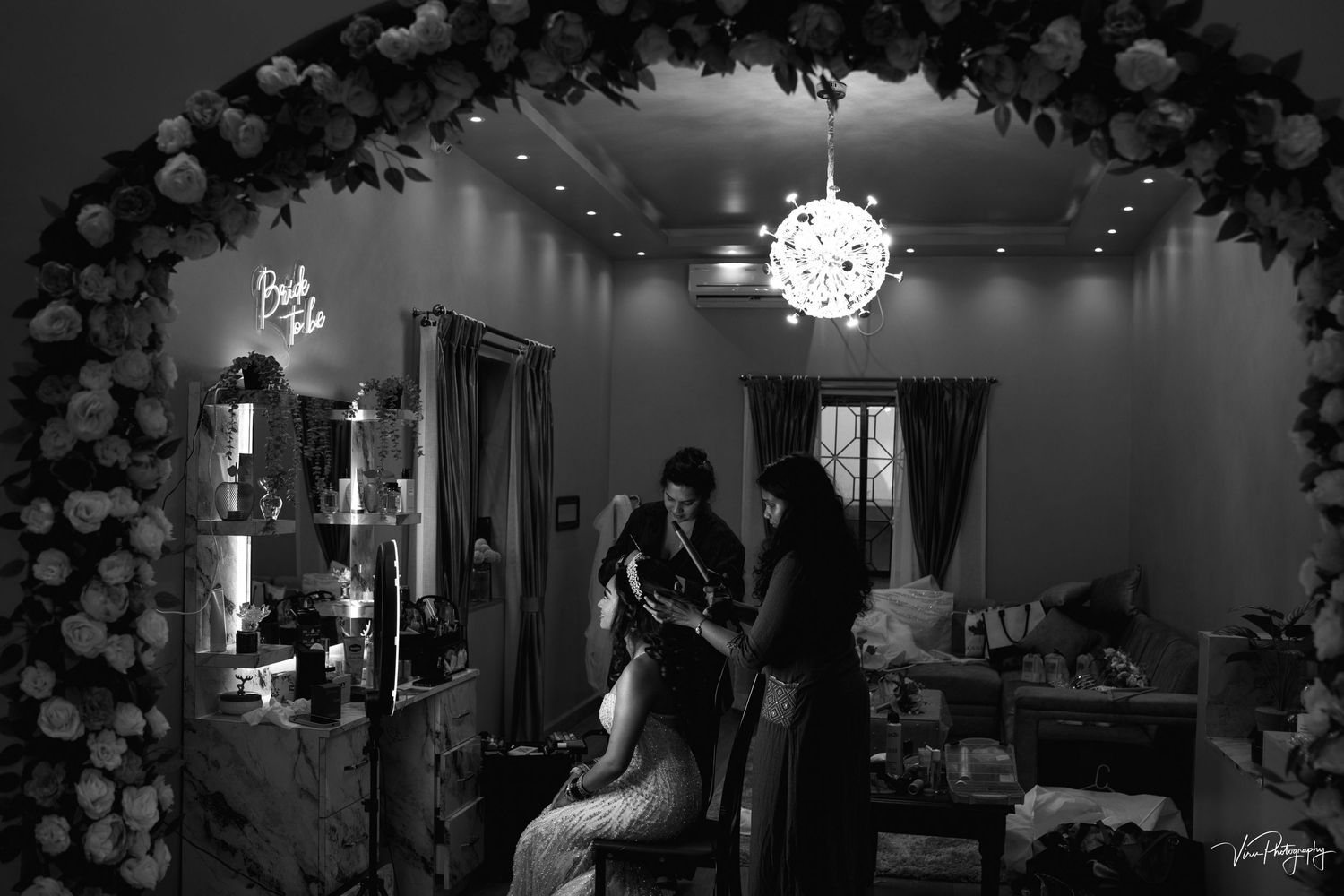 Black and white photo of a beauty salon decorated with floral archway and disco ball lighting for an elegant event setup.