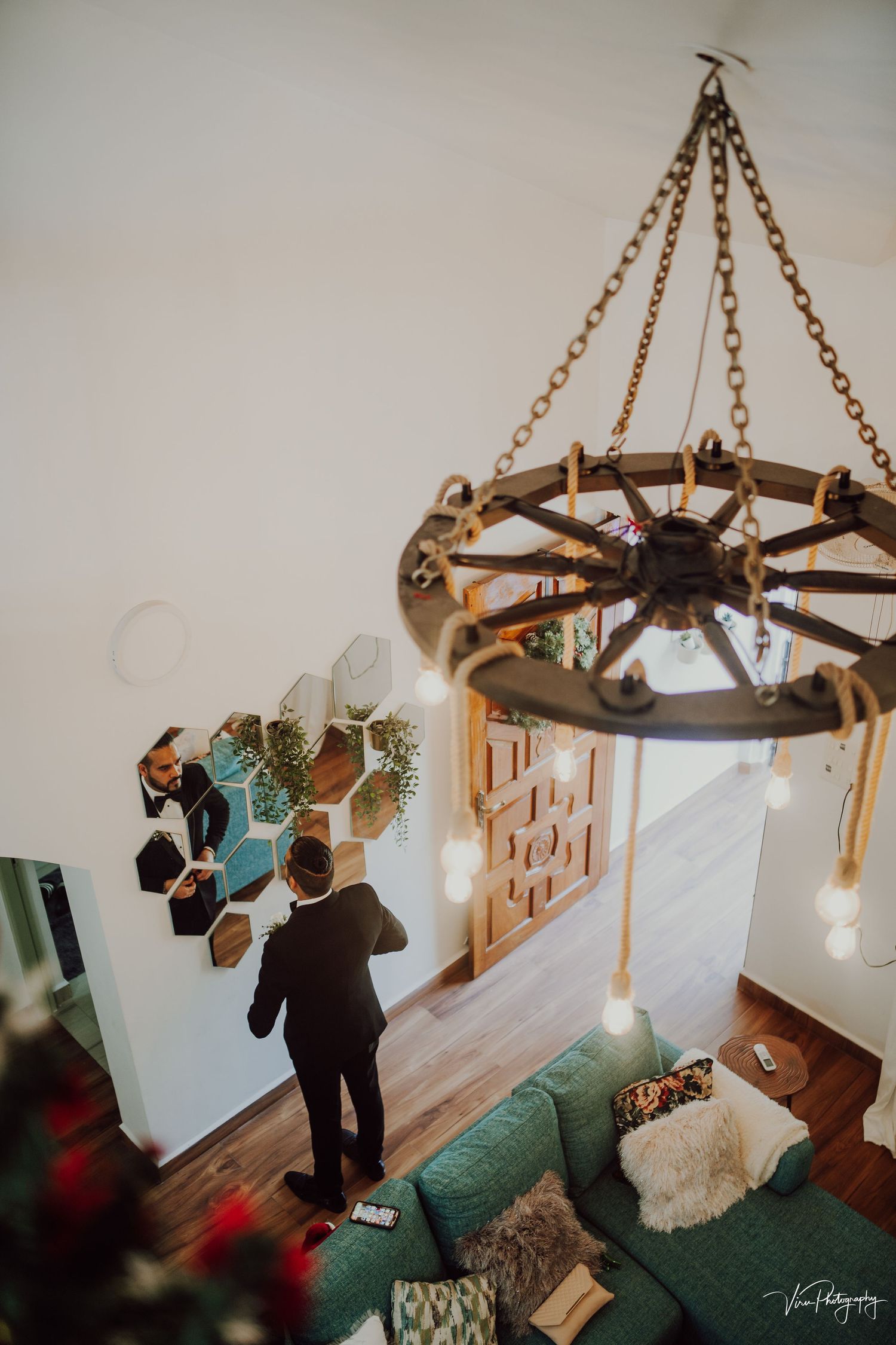 View from above of a modern living room with circular hanging light fixture, turquoise couch, and wall-mounted decor.