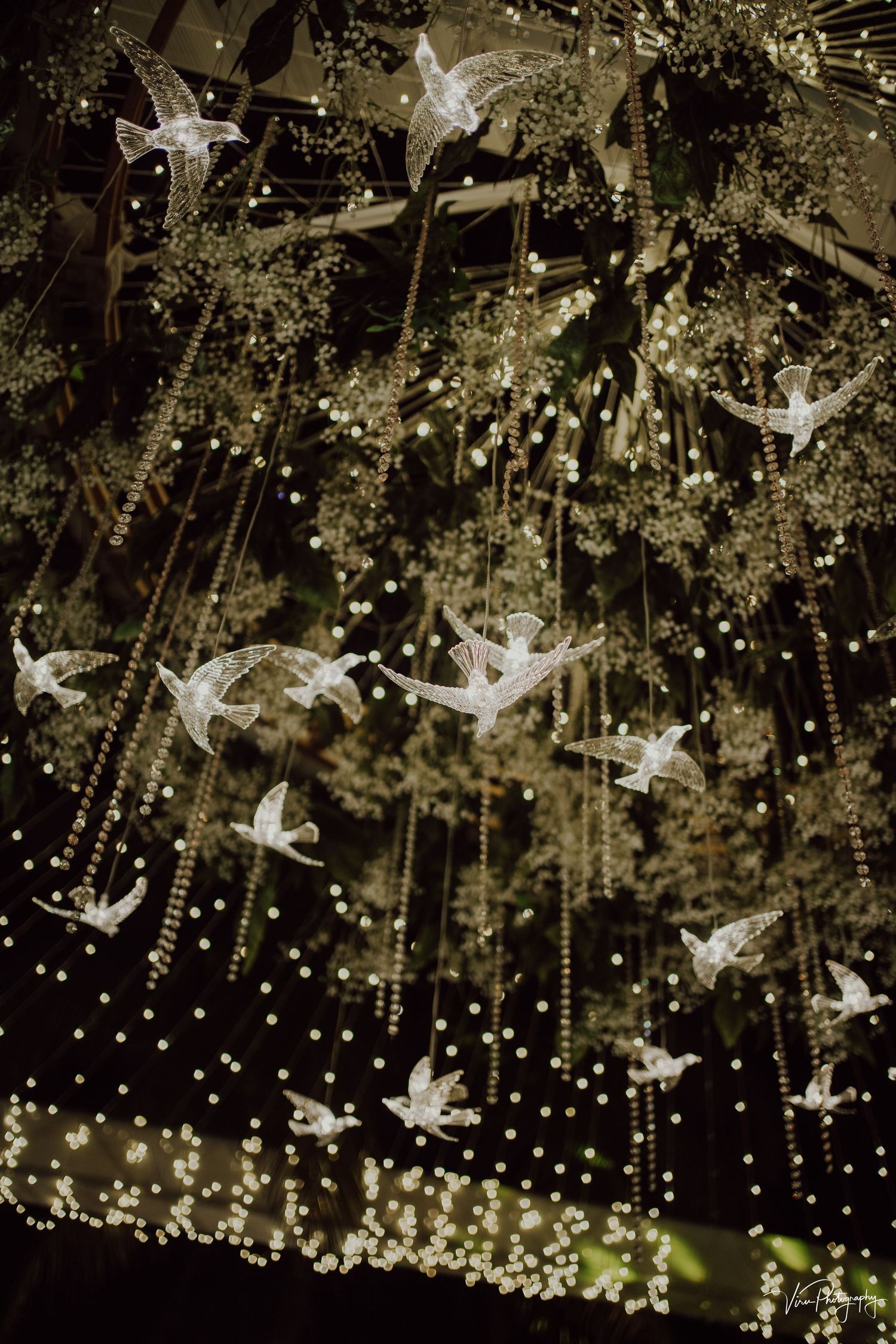 Ethereal white dove ornaments and sparkling lights create a magical holiday display against a dark background.