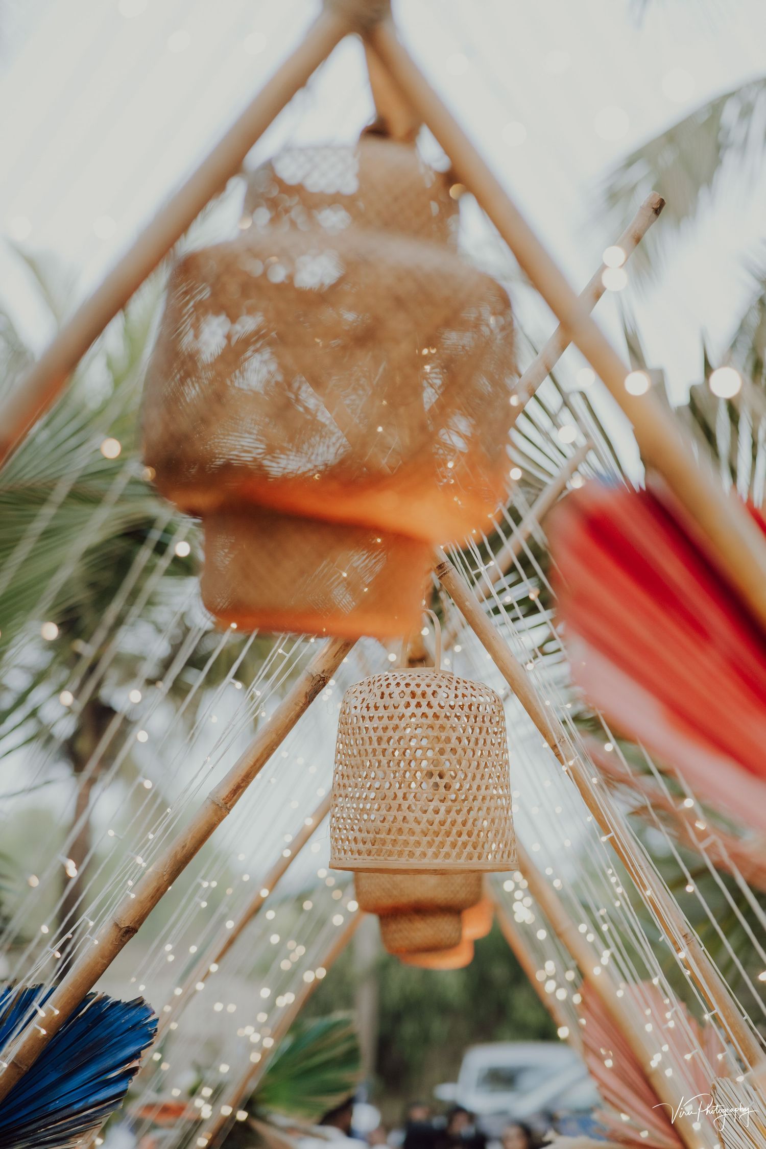 Decorative rattan pendant lamp with fairy lights and palm leaves creating a dreamy bohemian atmosphere.