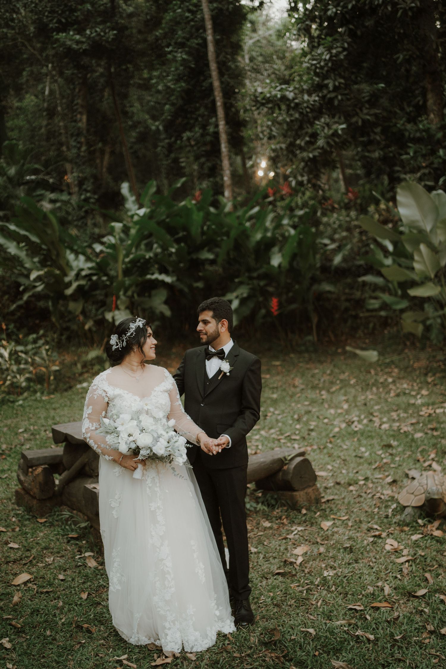 A romantic wedding photoshoot in a lush forest garden with wooden benches.