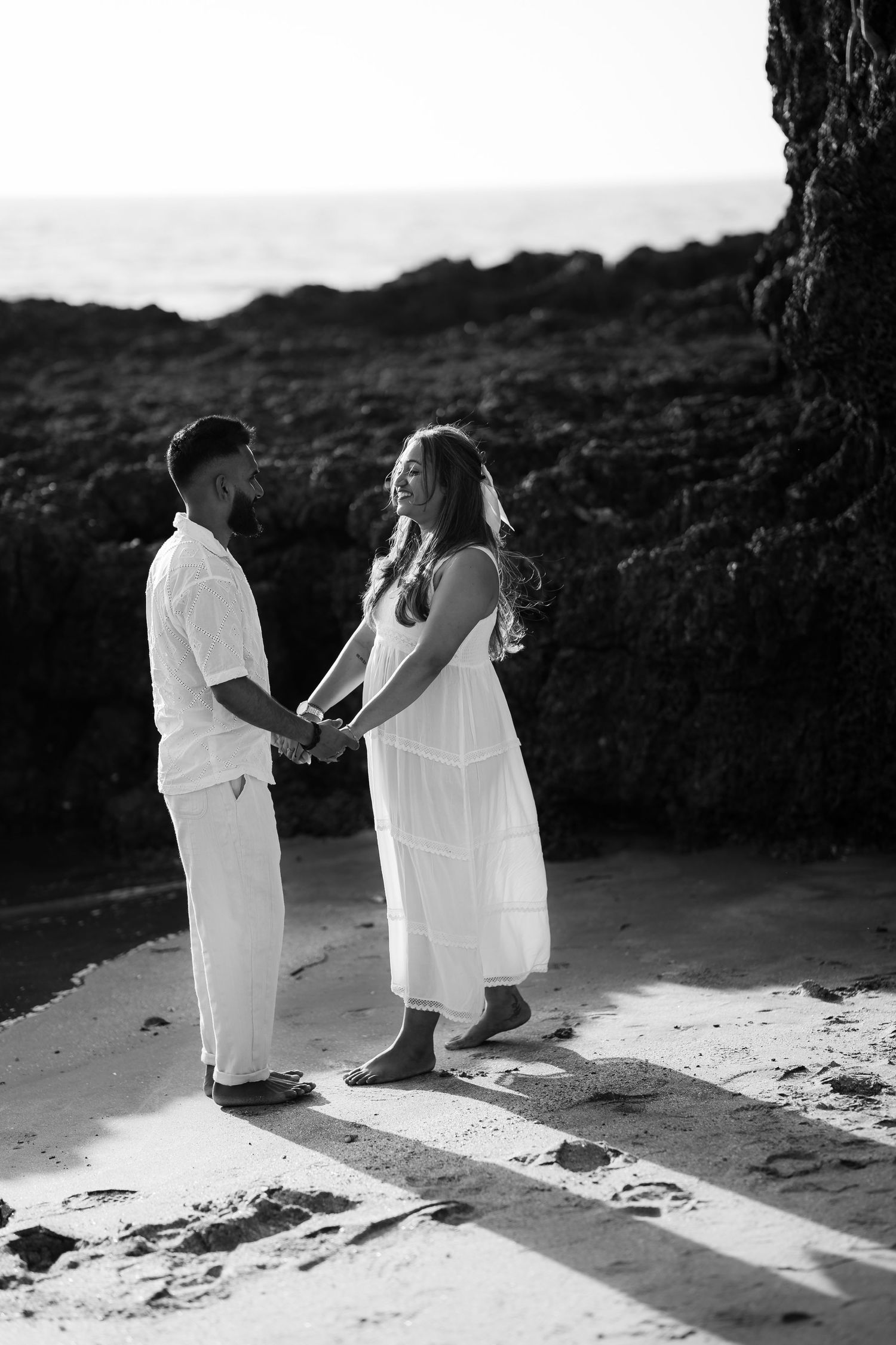 A romantic black and white photo sequence shows a couple in white clothing dancing together on a beach at sunset.