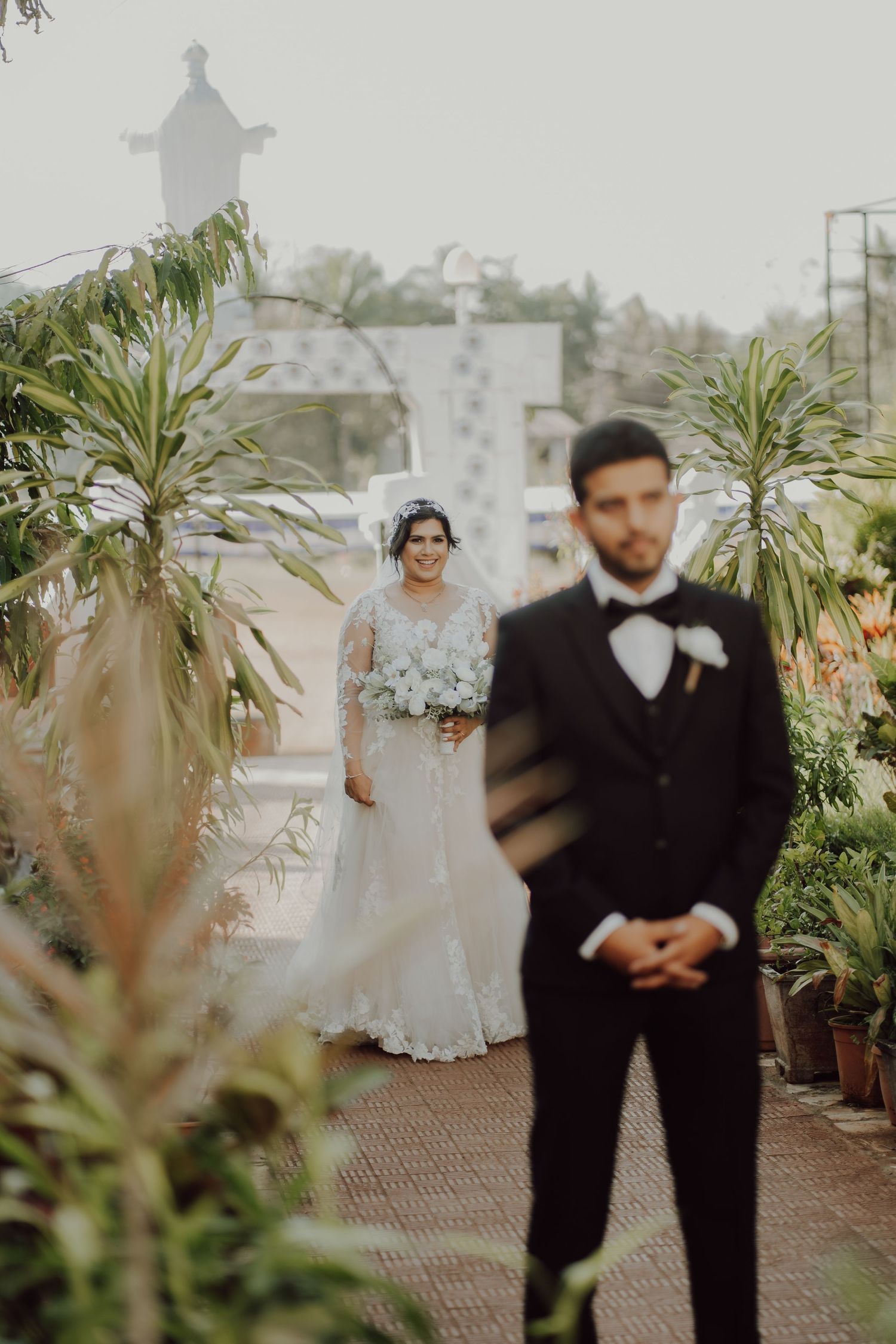 First look wedding moment in a garden setting with tropical plants.