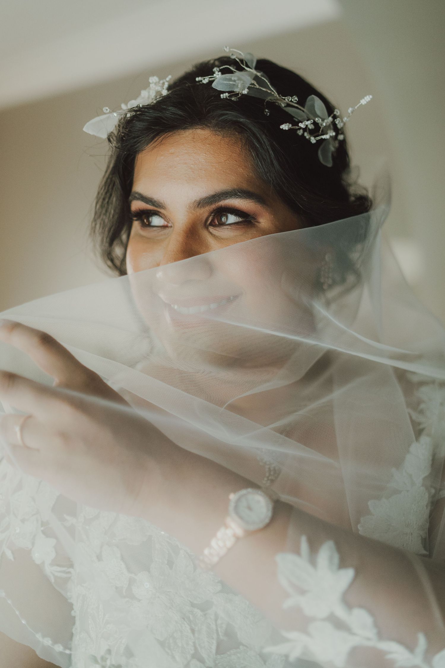 Close-up portrait of a bride with a delicate veil and crystal headpiece looking to the side.