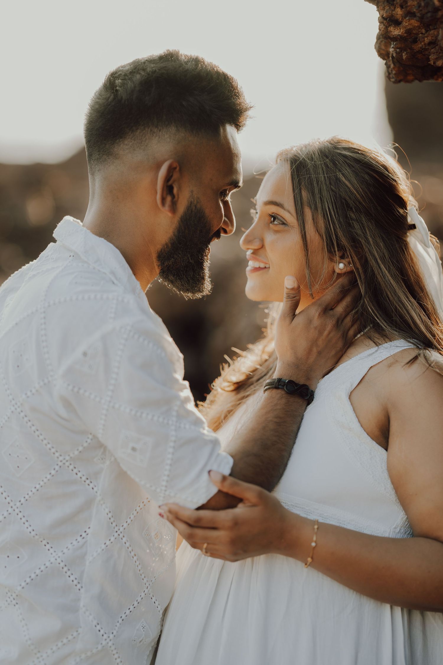 A romantic couple in white outfits share intimate moments in a series of candid sunset photos.