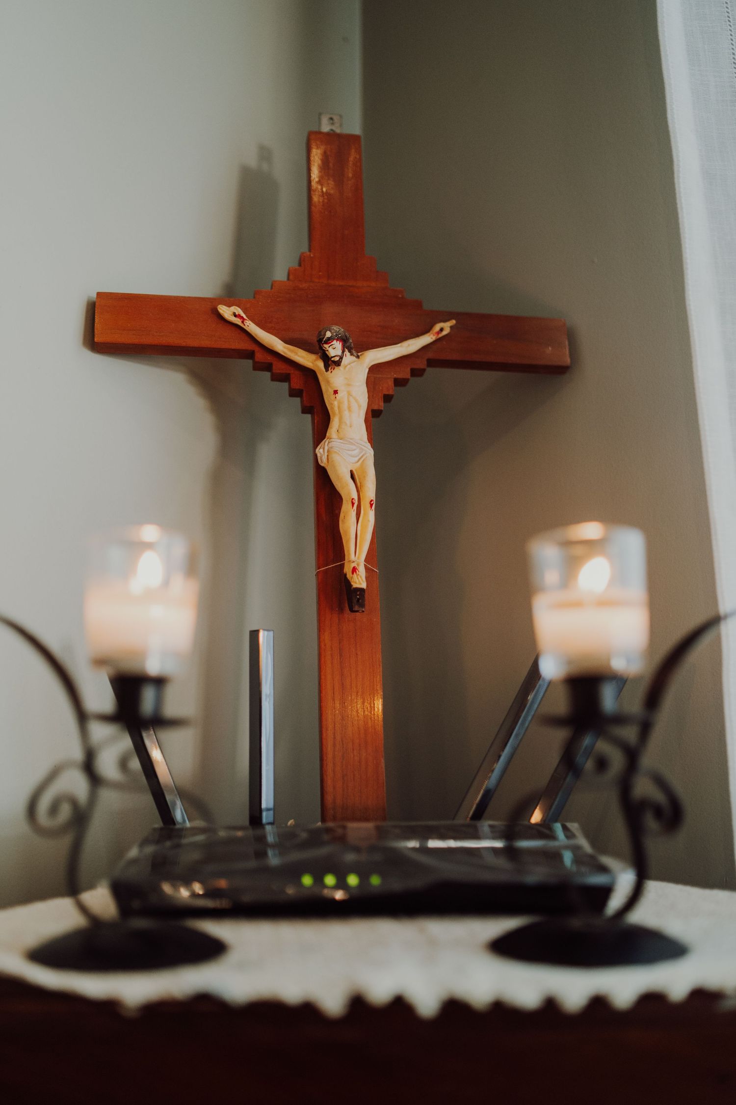 A wooden crucifix flanked by candles on display with a router in the foreground.