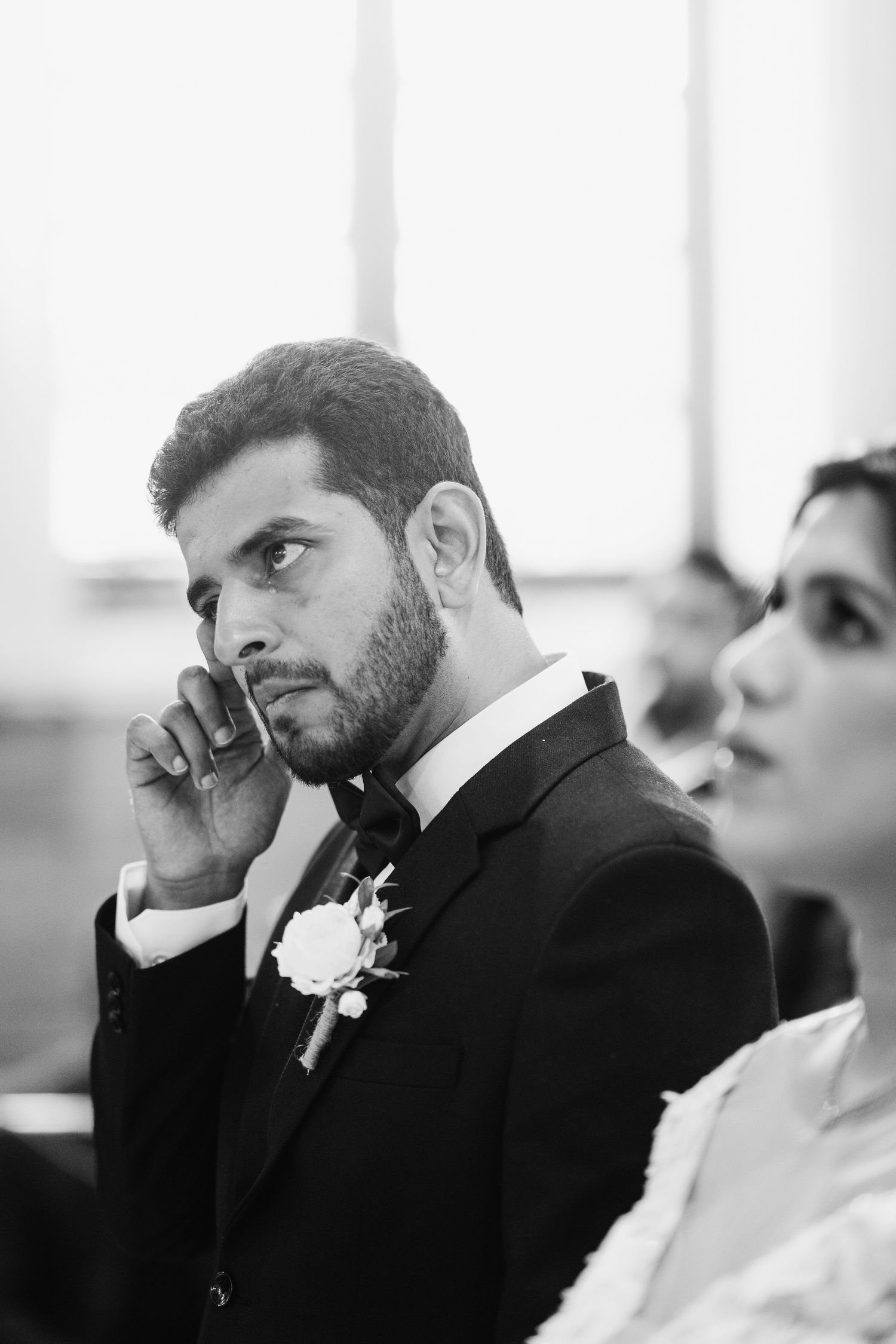 A black and white portrait of a formally dressed person at a wedding ceremony.