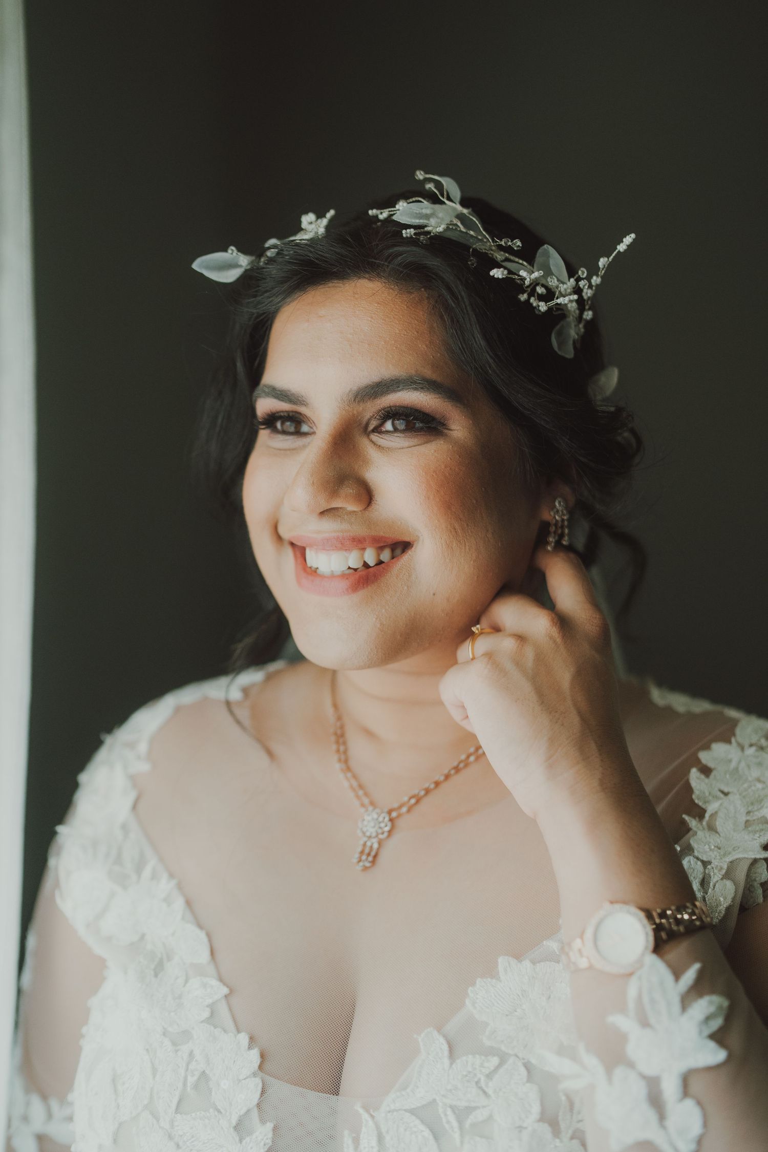 A bridal portrait showcasing a delicate crystal headpiece and lace wedding dress details.