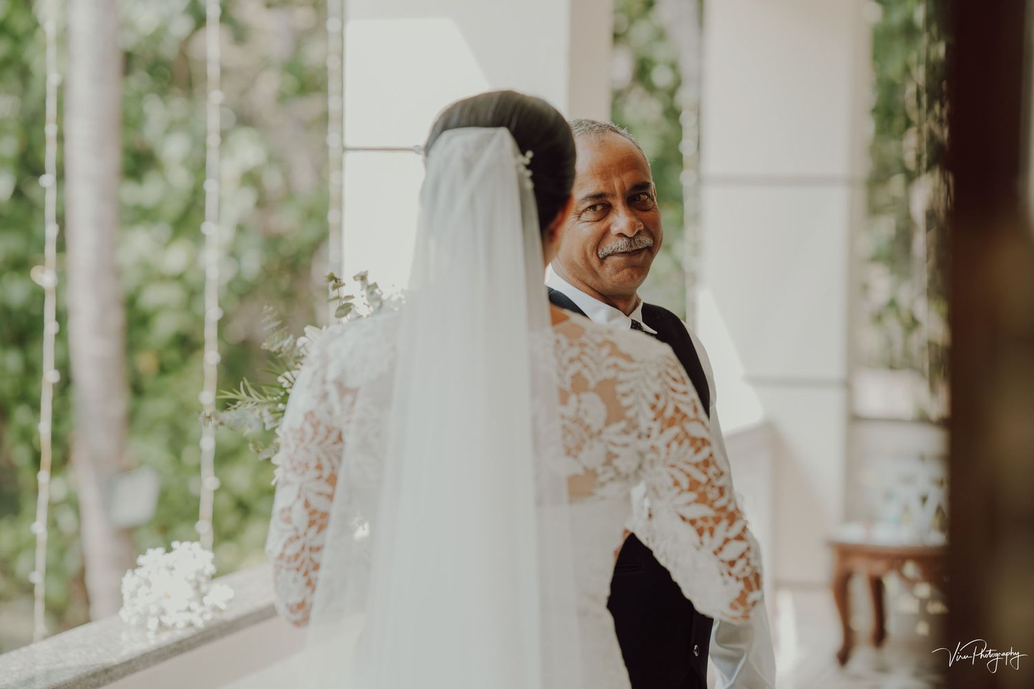 Two people sharing an emotional moment during a wedding ceremony with floral decor and long white veil.