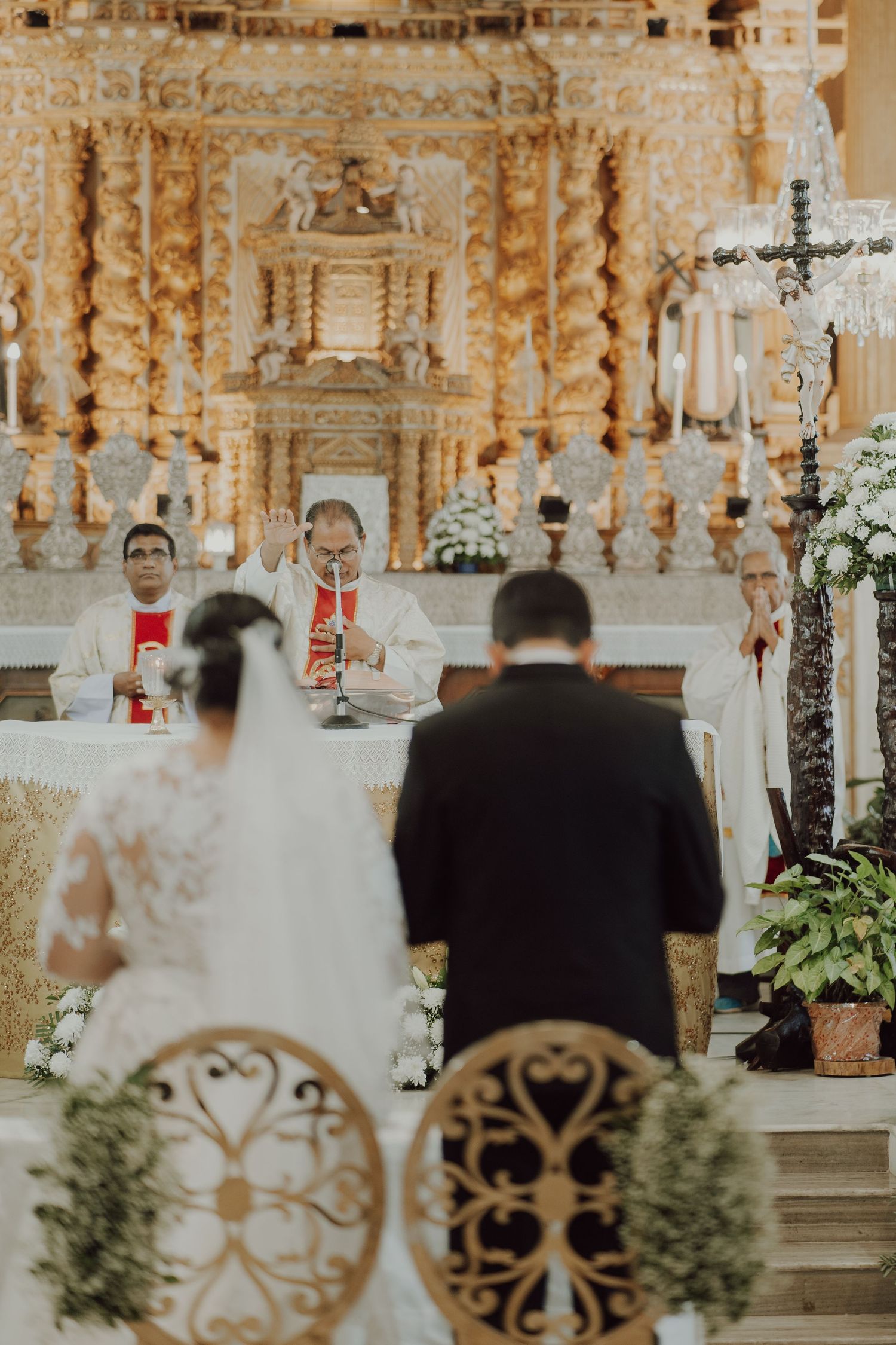 A Catholic wedding ceremony at an ornate golden altar with clergy officiating.