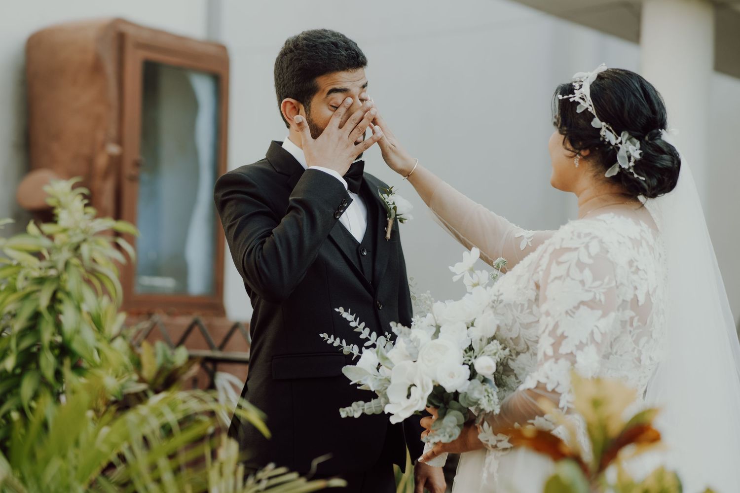 An emotional wedding moment captured between a couple in formal attire with white floral bouquet.