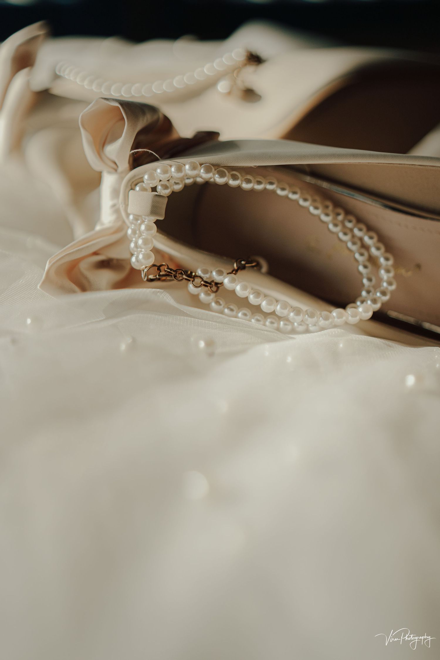 A delicate pearl necklace rests elegantly on cream-colored fabric with soft lighting creating a romantic mood.