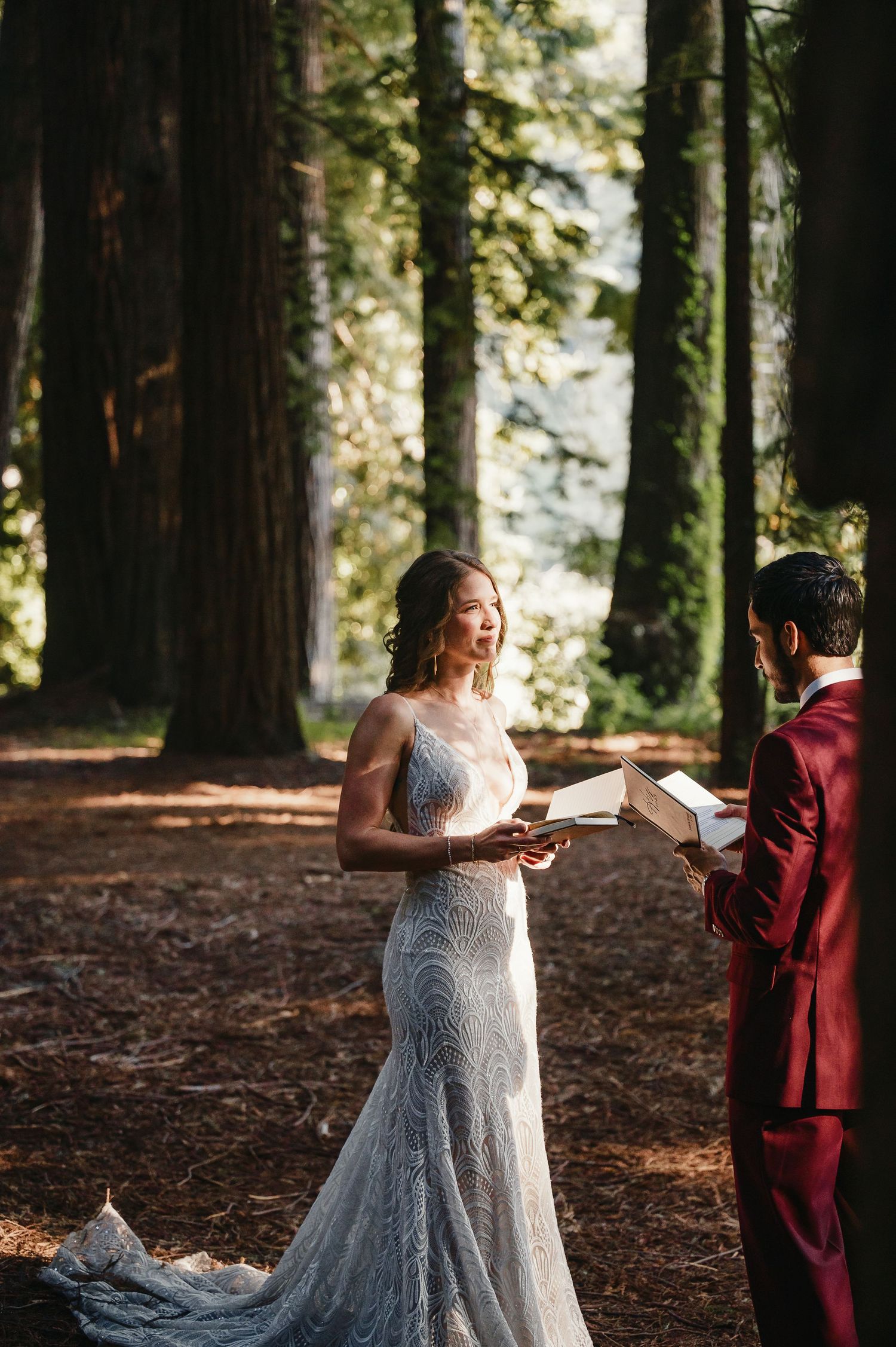 A couple exchanges vows during an intimate forest wedding ceremony surrounded by towering redwood trees.