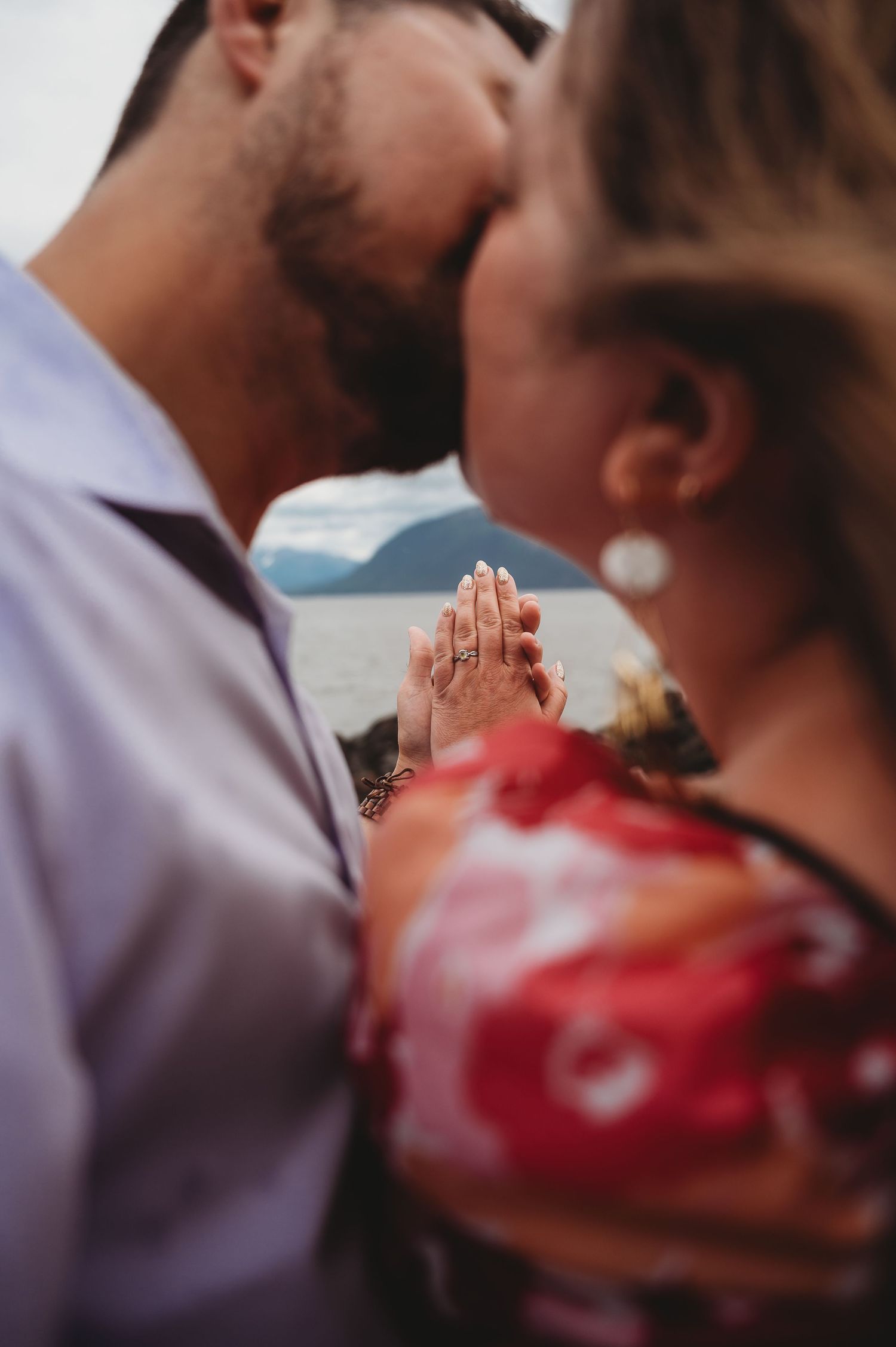 A close up shot of clasped hands showing intimacy between two people wearing a red dress and light colored shirt.