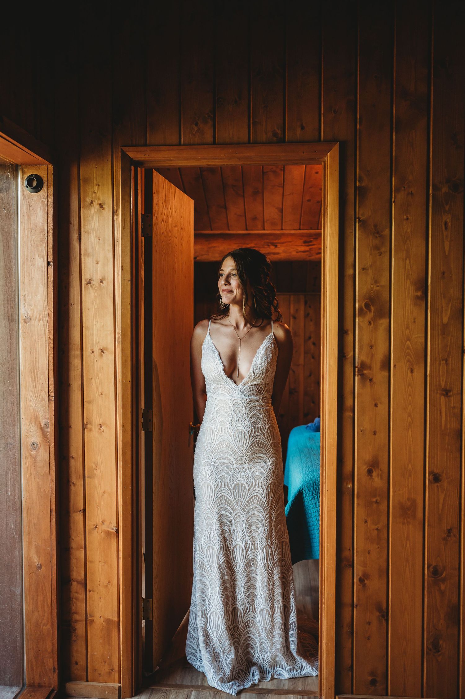 White lace bridal gown displayed in front of wooden cabin walls.