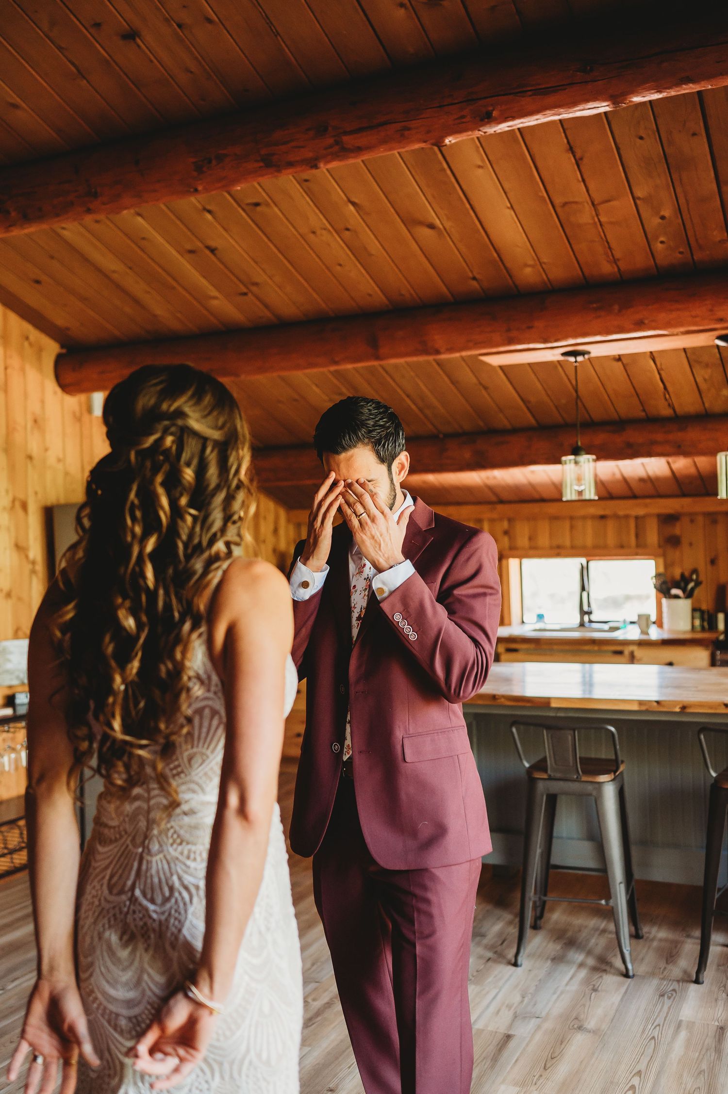 A couple in formal attire sharing a private moment in a rustic wooden interior venue.