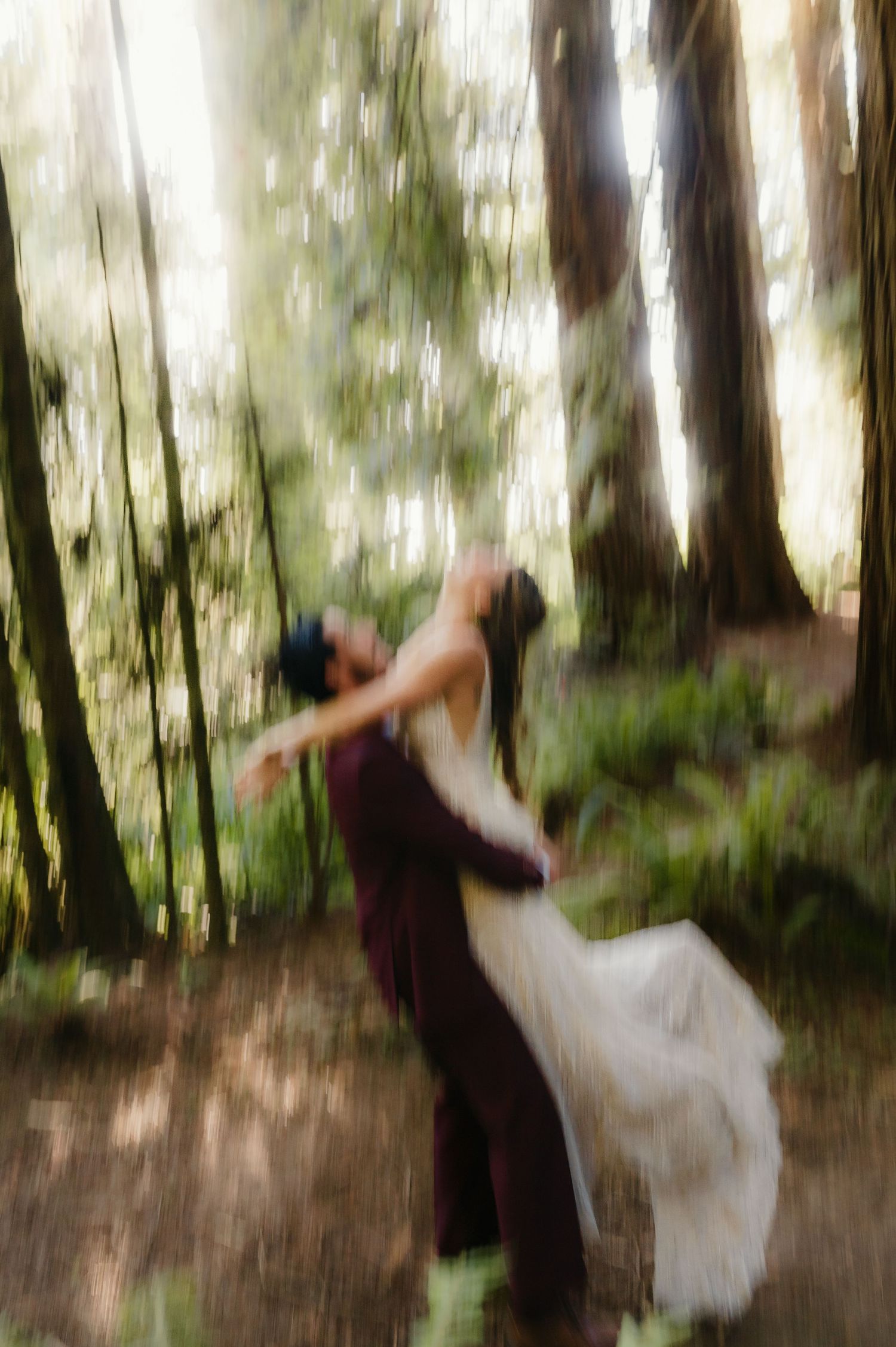 Abstract motion-blurred figures dancing in a dreamy forest setting with soft white and green tones.