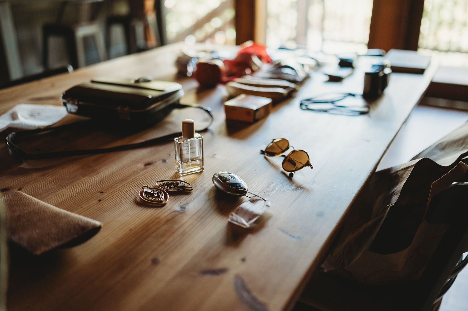 Rustic wooden desk scattered with various items and papers in natural sunlight.