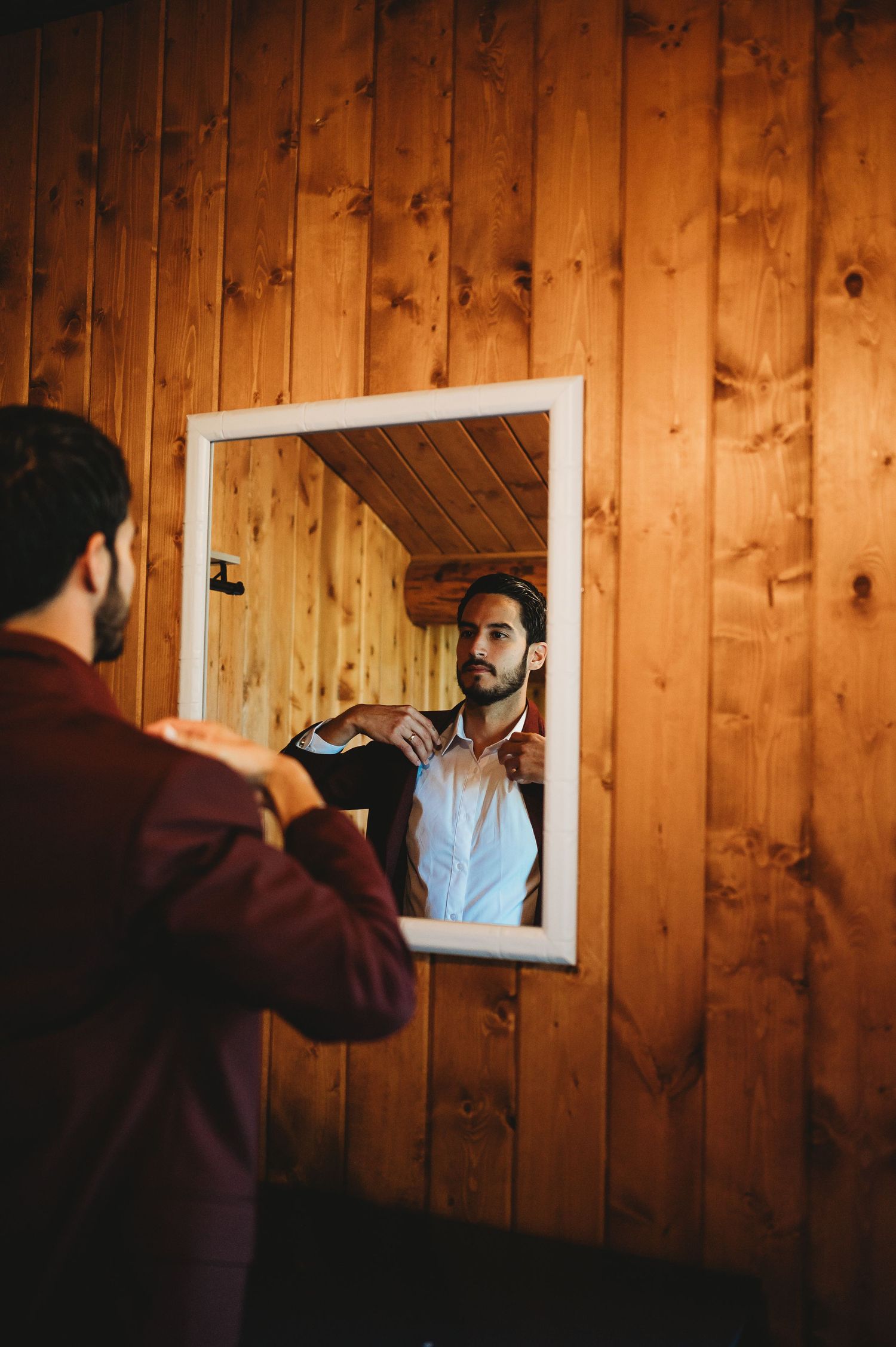 A series of shots showing a person adjusting their bowtie while looking in a small mirror mounted on wooden paneled walls.