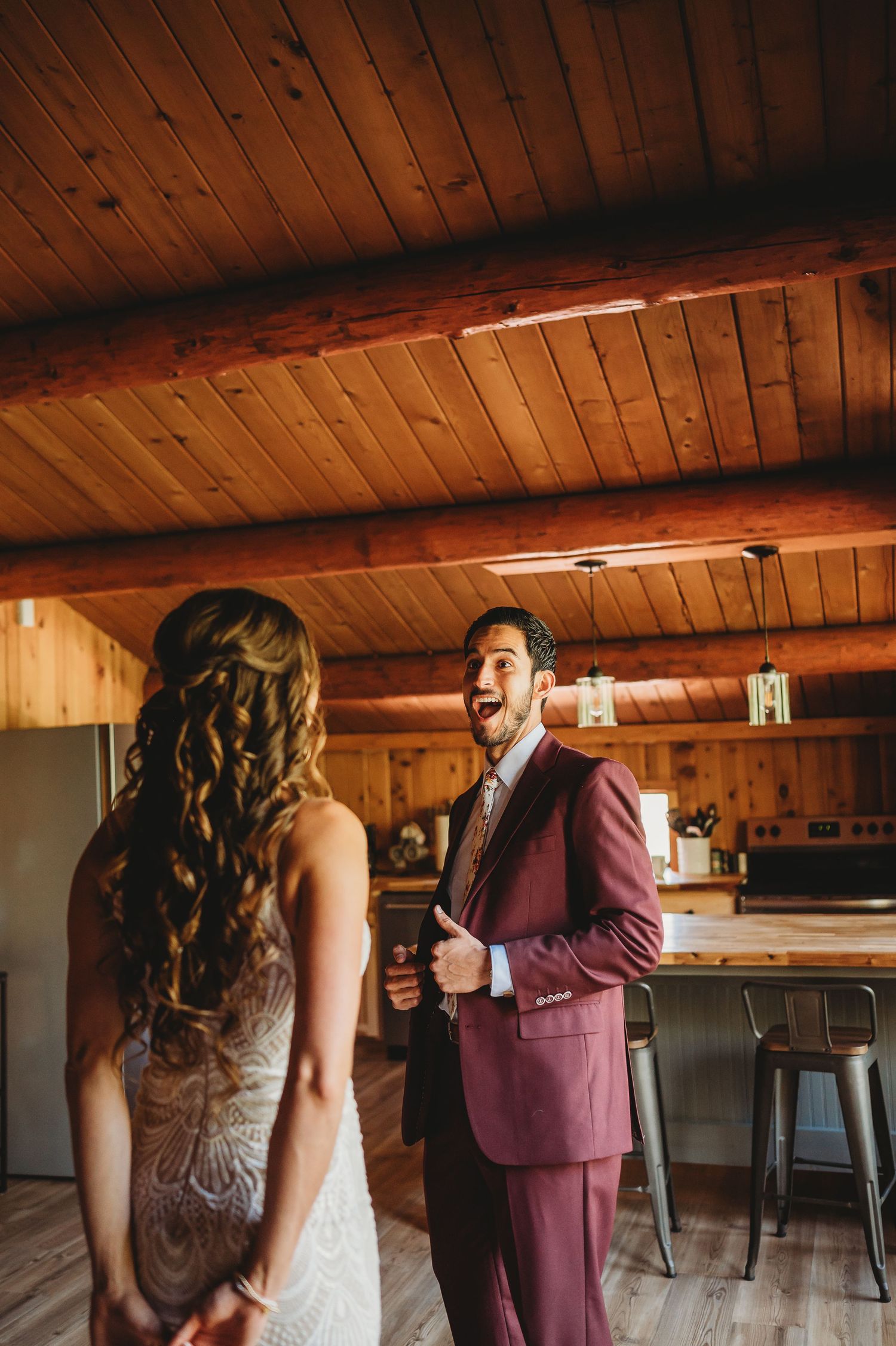 First look moment in rustic cabin with wooden walls and ceiling beams.