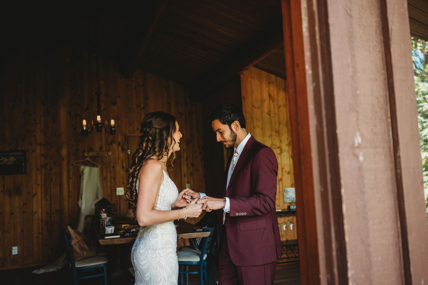 Emotional wedding first look moment captured in rustic log cabin setting.