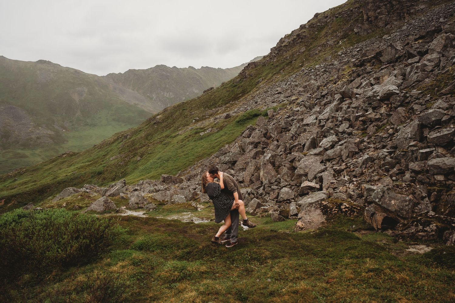 Dramatic mountain landscape with rocky cliffs and winding paths through rugged alpine terrain.