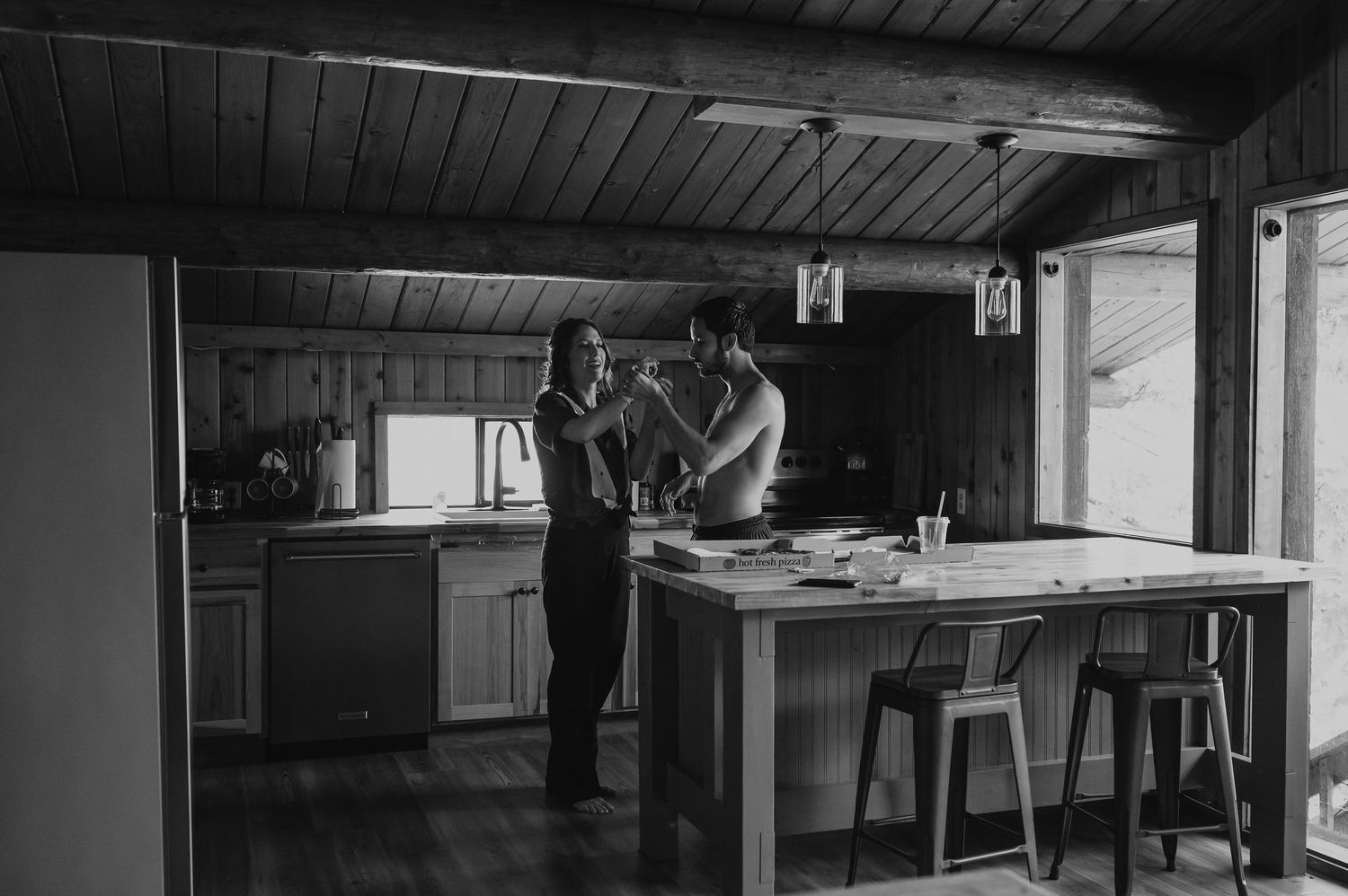 Black and white panoramic view of a rustic dance hall interior with wooden beams and exposed ceiling.