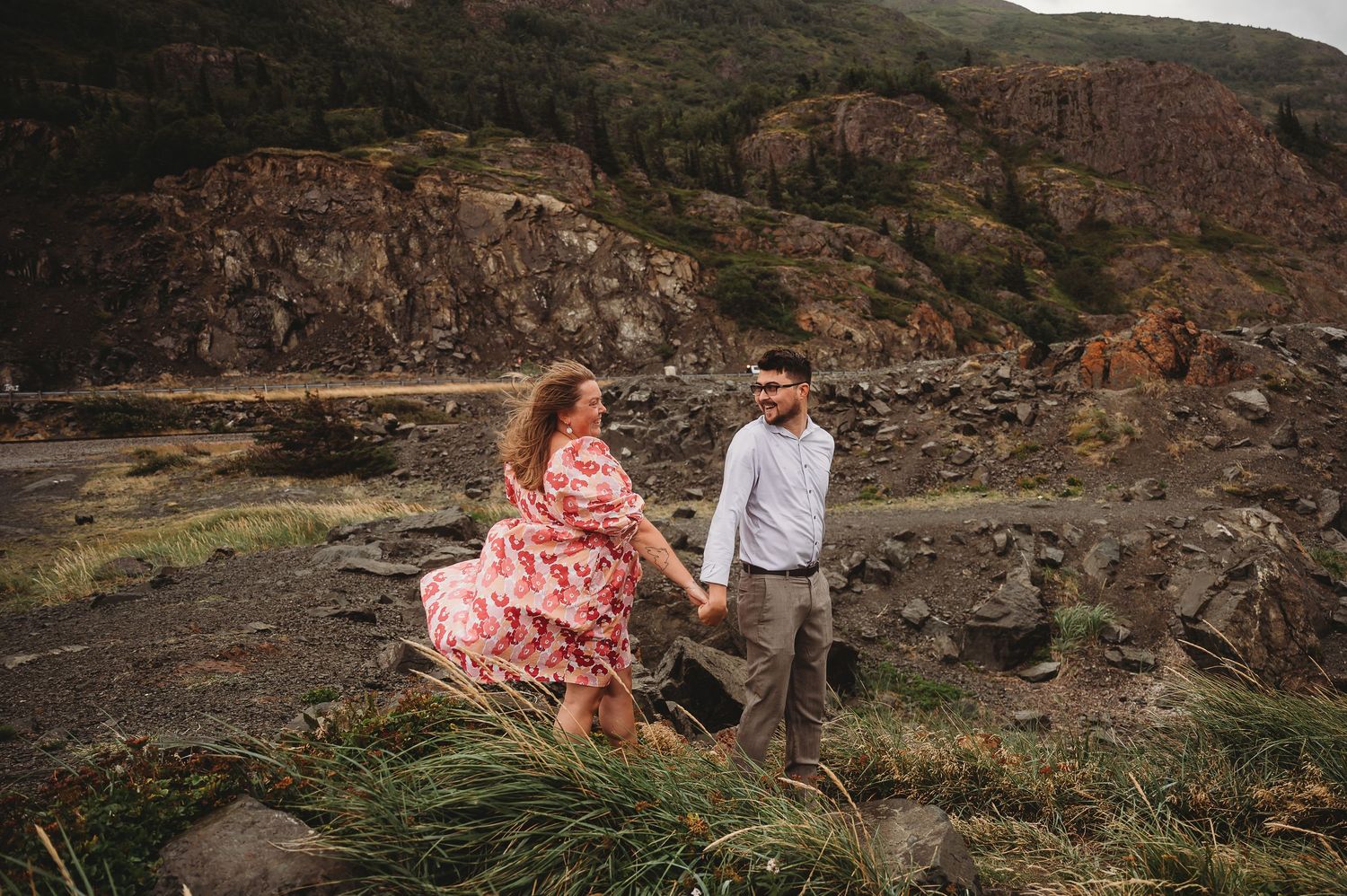 Couple enjoying a romantic dinner on a rugged mountain overlook with scenic valley views at sunset.