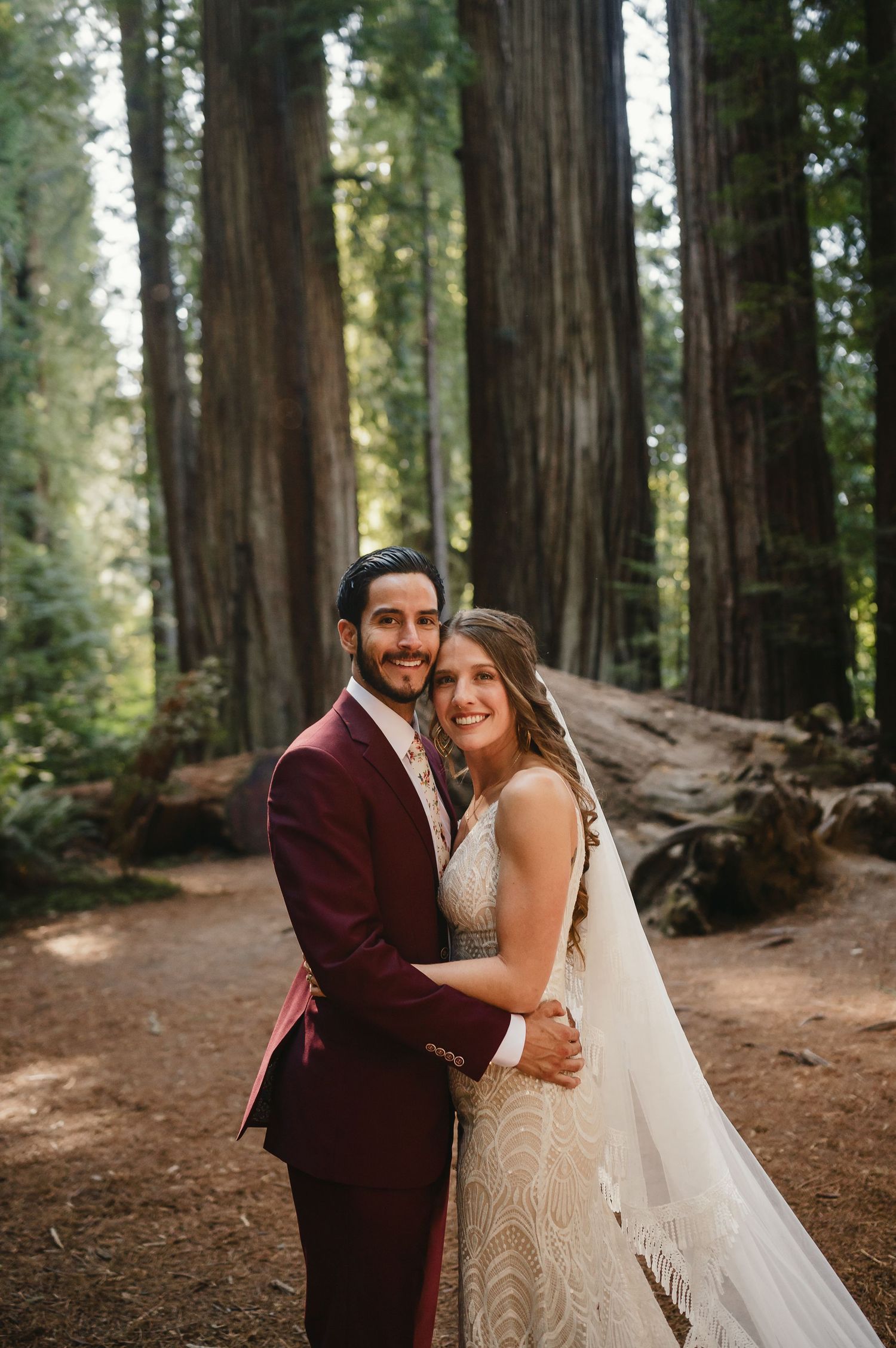 Newlyweds share an intimate moment beneath majestic redwood trees on their wedding day.