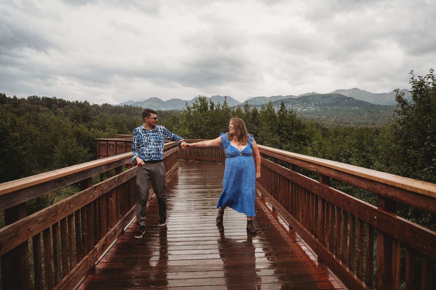 Two people walk along a scenic mountain overlook boardwalk in western North Carolina on a cloudy afternoon.