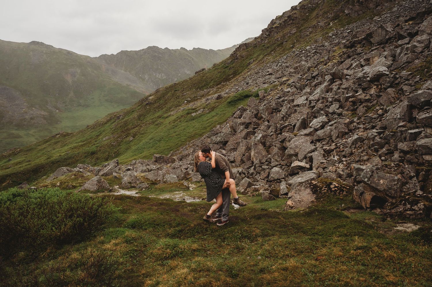 A scenic mountain trail cuts through rocky slopes and green alpine meadows.