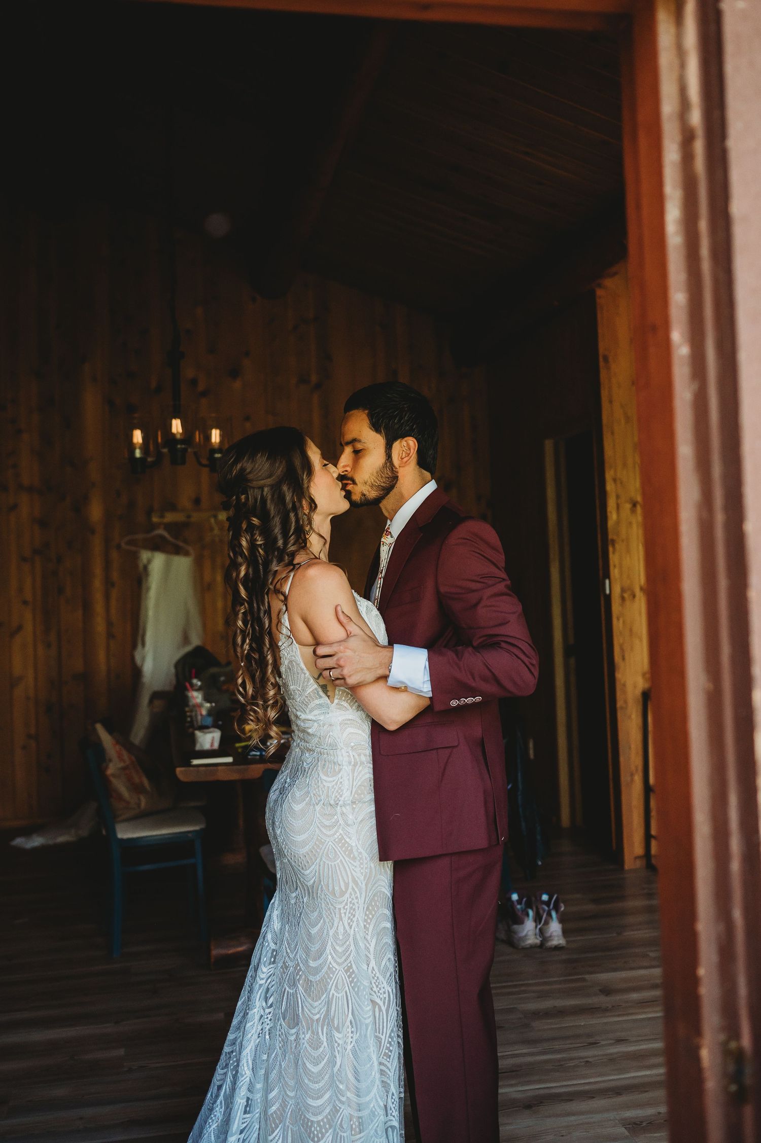 A wedding couple sharing their first dance in a dimly lit wooden reception hall.