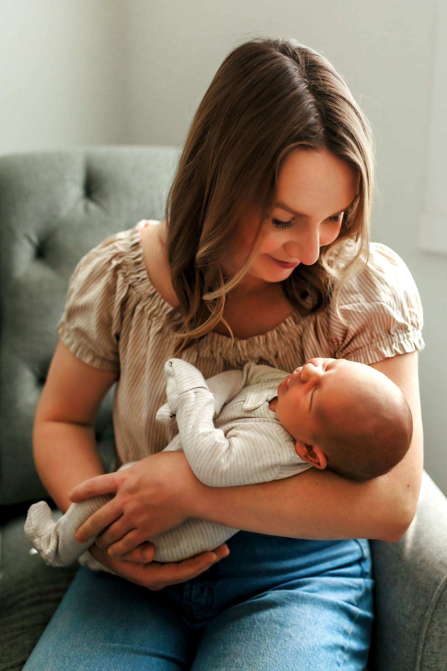 Lifestyle newborn portraits featuring a mother cuddling her baby during an at-home Calgary session.