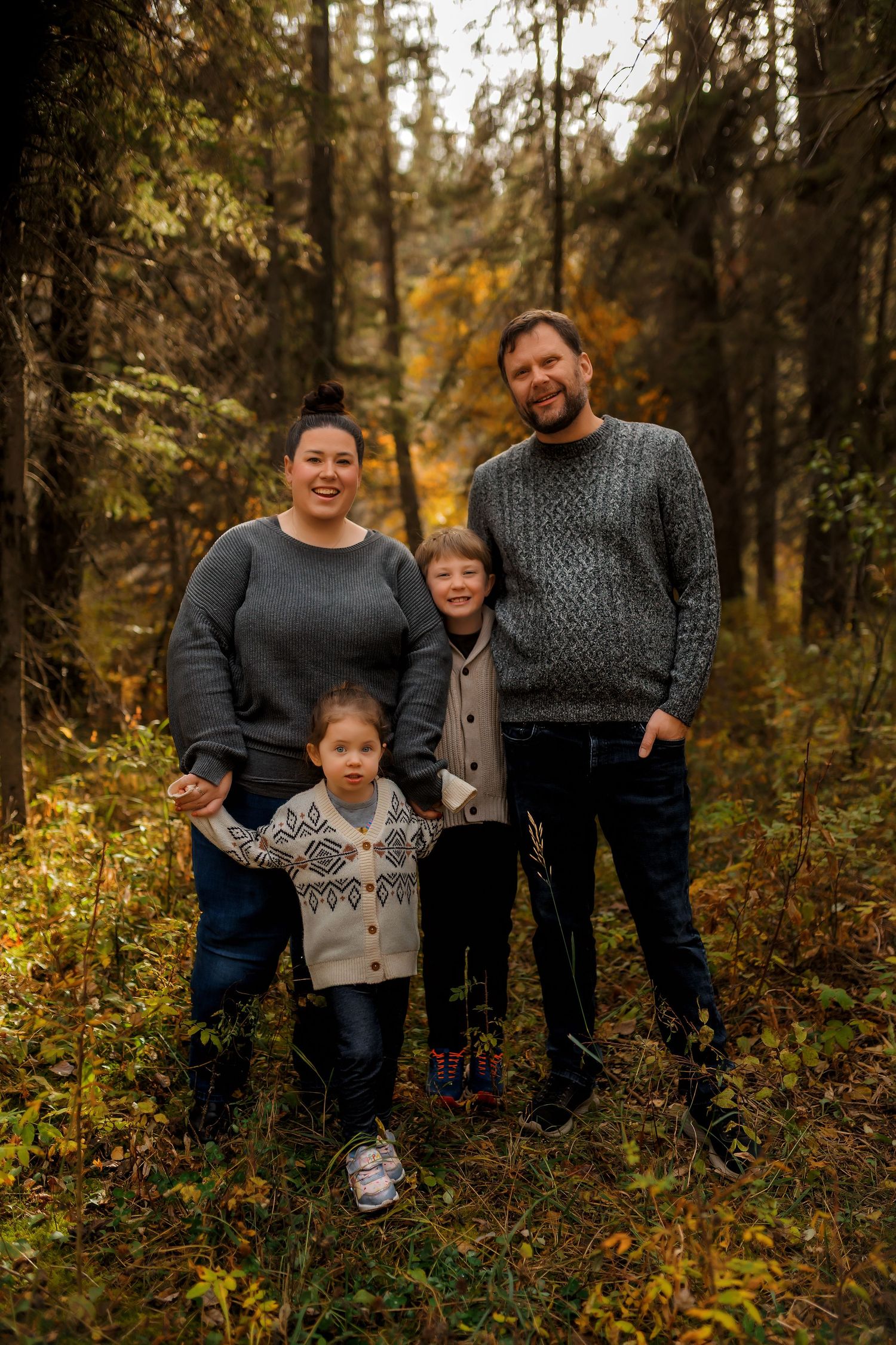 Calgary family surrounded by tall trees and soft light during their forest session at Shannon Terrace Park.
