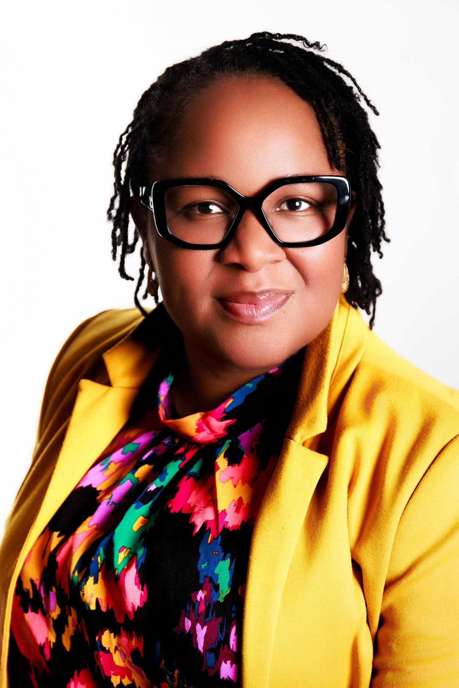 Person in bright yellow jacket and colorful patterned scarf smiling in studio portrait series against white background.