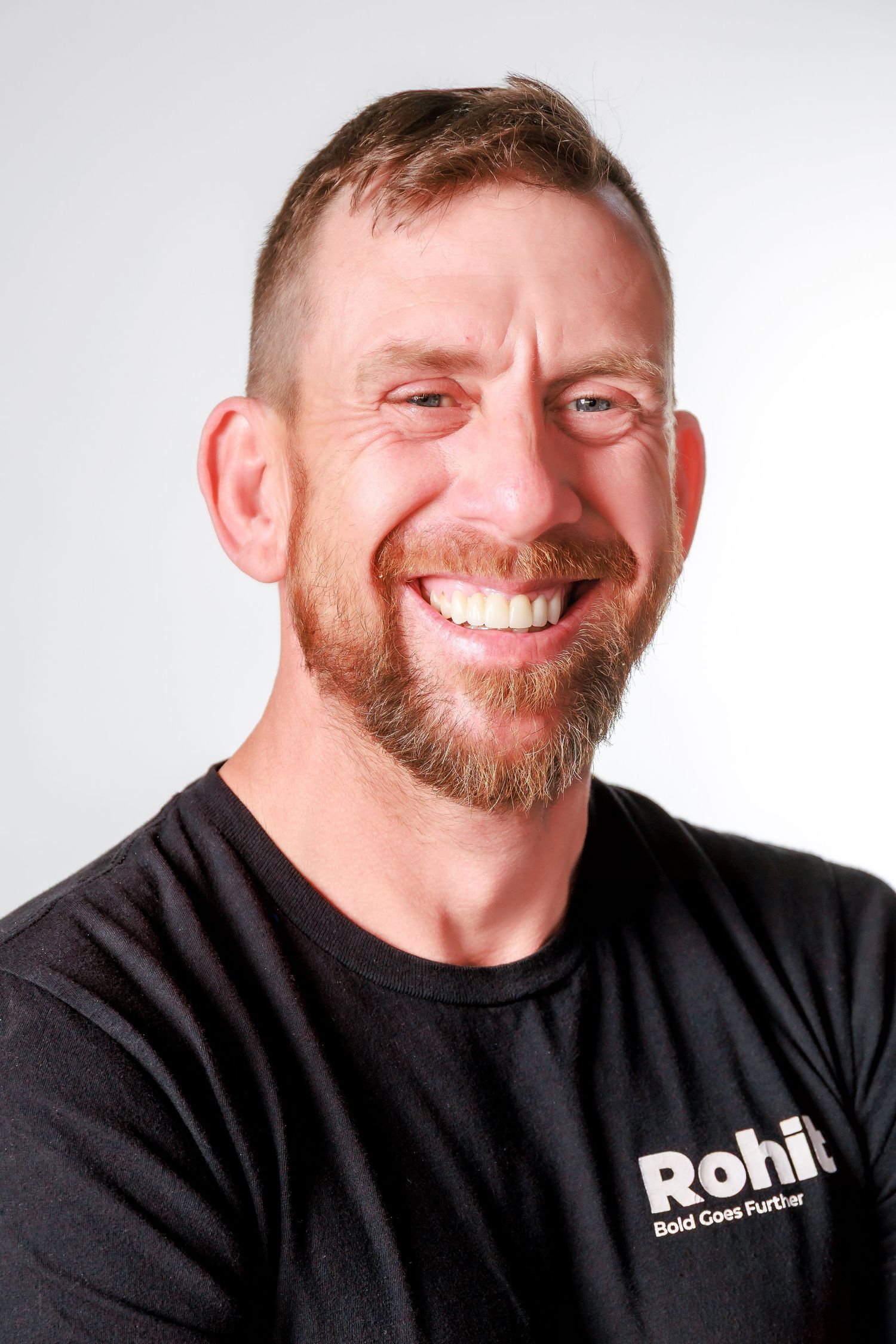 A series of four headshots showing someone wearing a black t-shirt smiling with a beard.