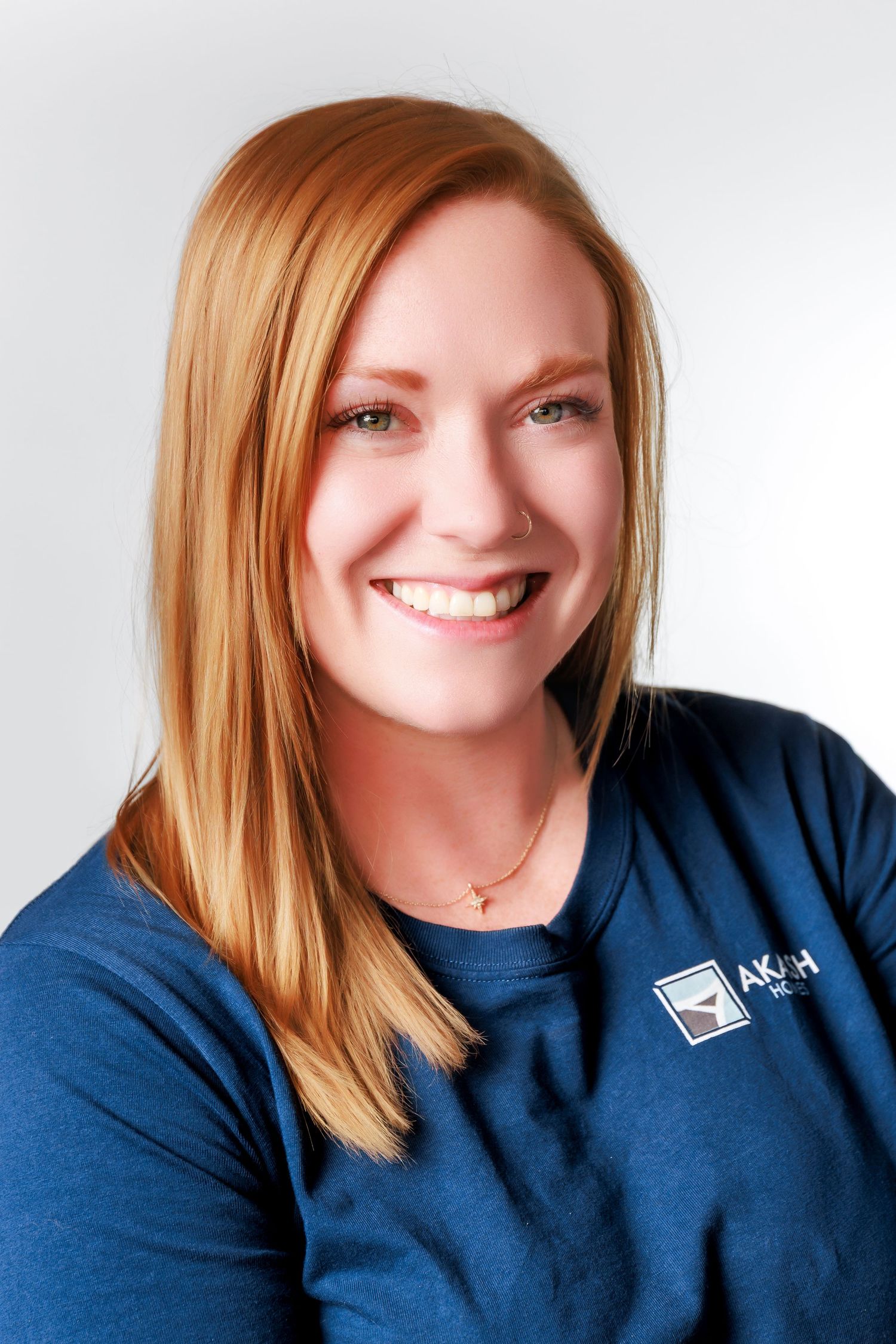 Four headshots of someone with red hair wearing a navy blue shirt and smiling warmly at the camera.
