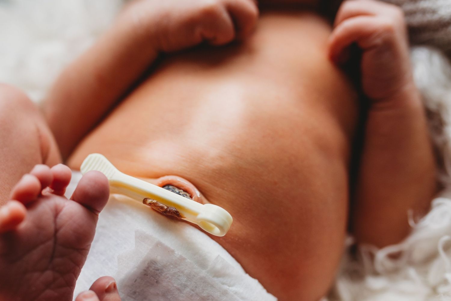 Baby holding a teething toy or pacifier in their tiny hand with soft natural lighting.