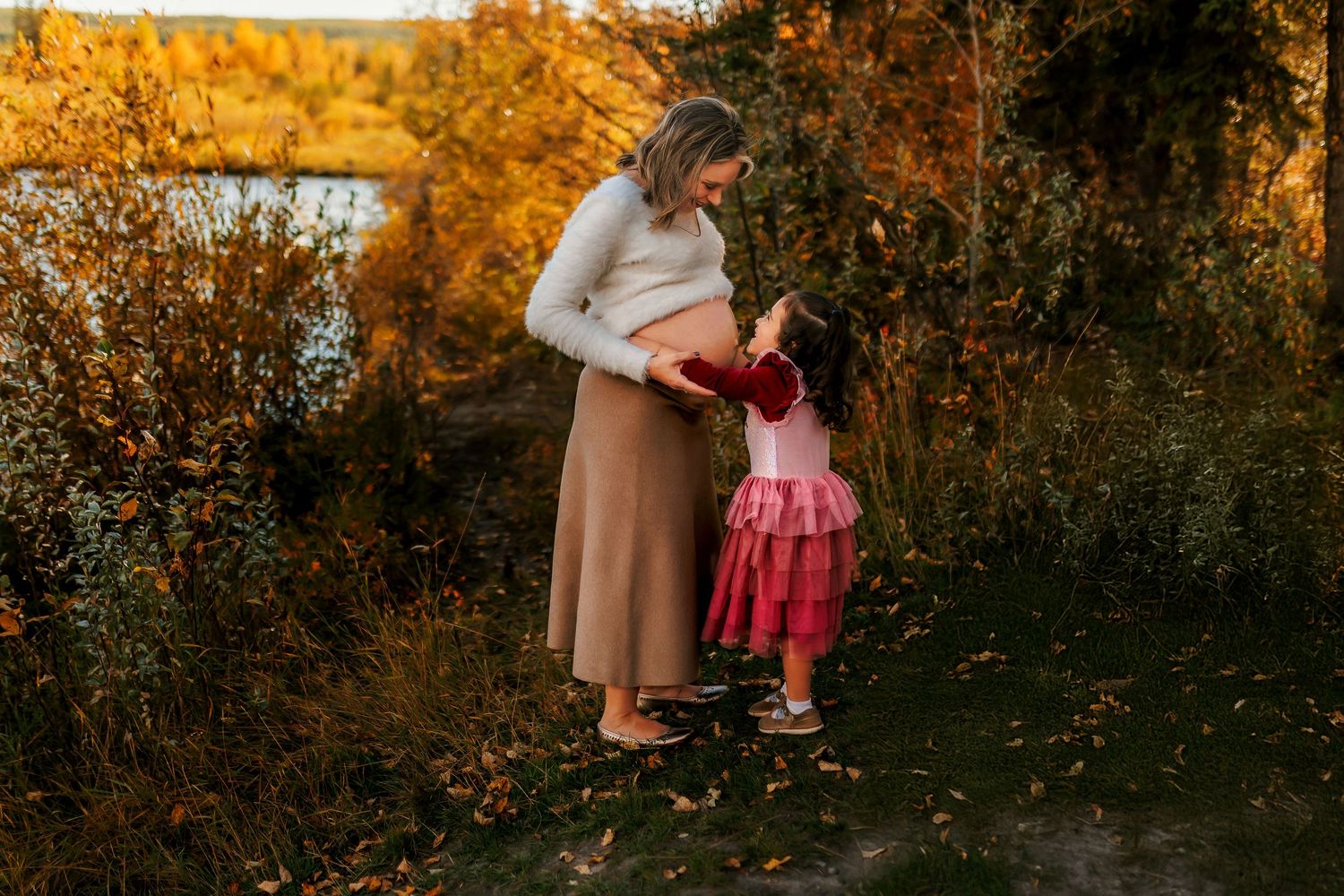 Two figures share a tender moment at sunset in an autumn meadow with golden foliage in the background.
