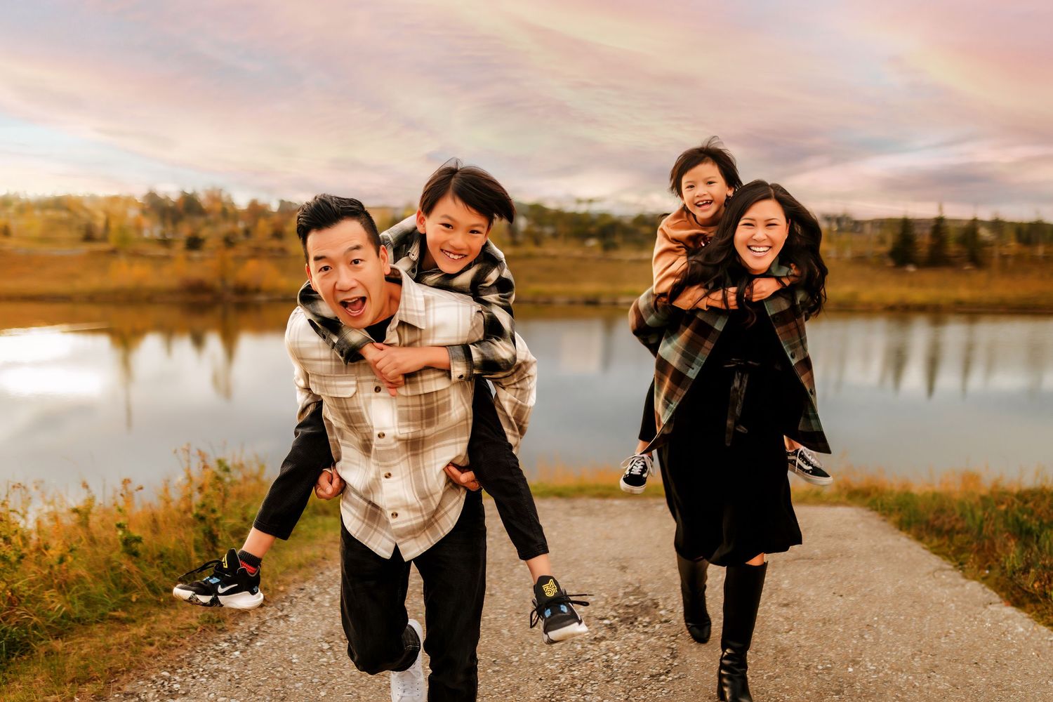 Family running happily in front of a lake in Calgary, Alberta.