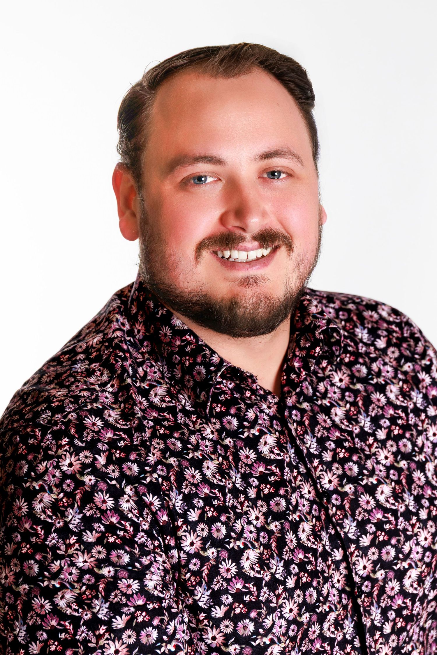 A series of progressive headshots showing someone wearing a black and pink floral print shirt against a white background.