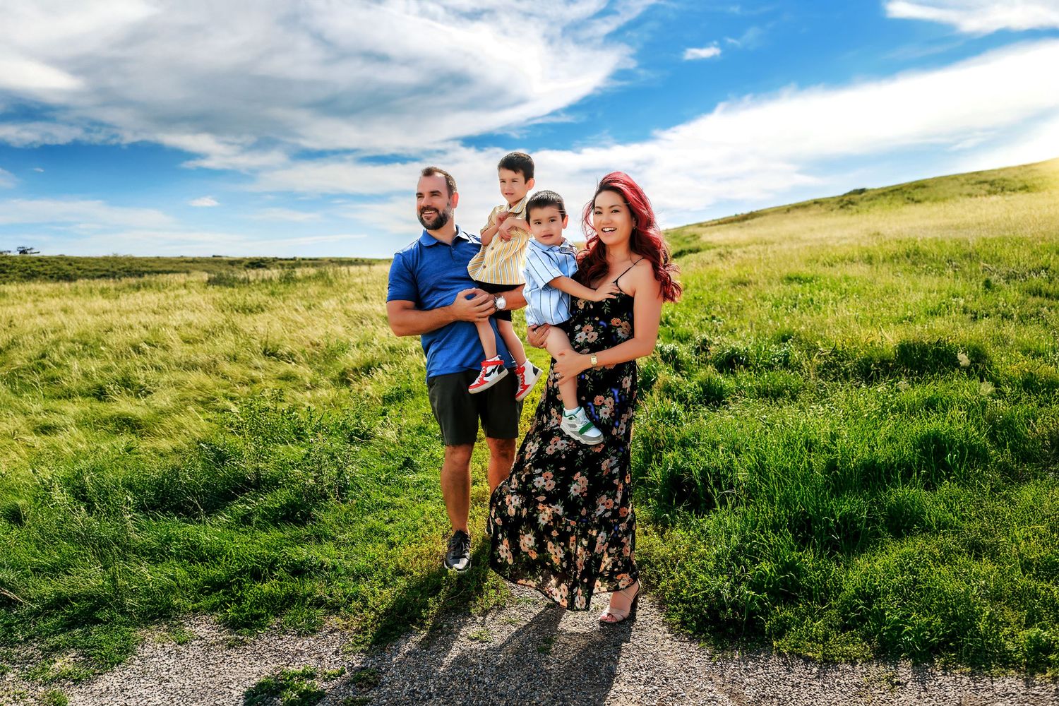 Family of four with two young boys smiling during a photography session at Nose Hill Park in Calgary.