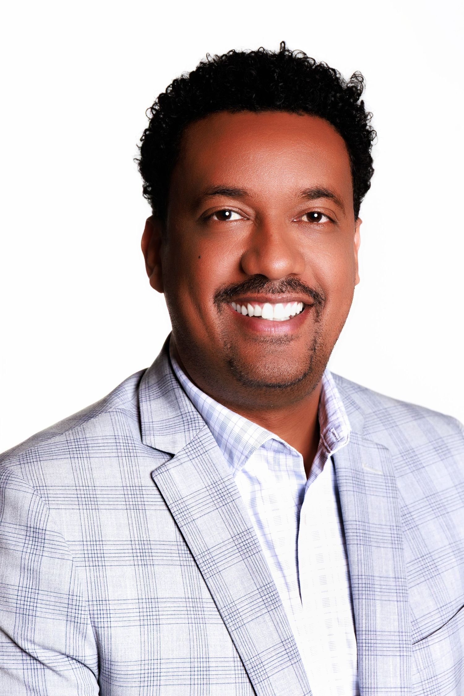 Three headshots of someone in a light gray plaid blazer showing different smiling expressions against white background.