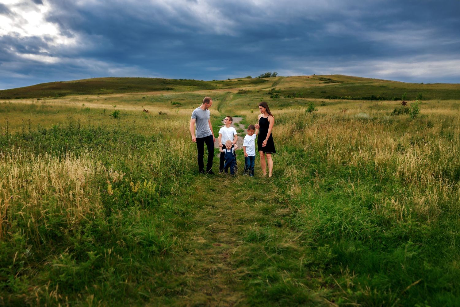 Family photography at Nose Hill Park in Calgary with dark moody clouds in the background.